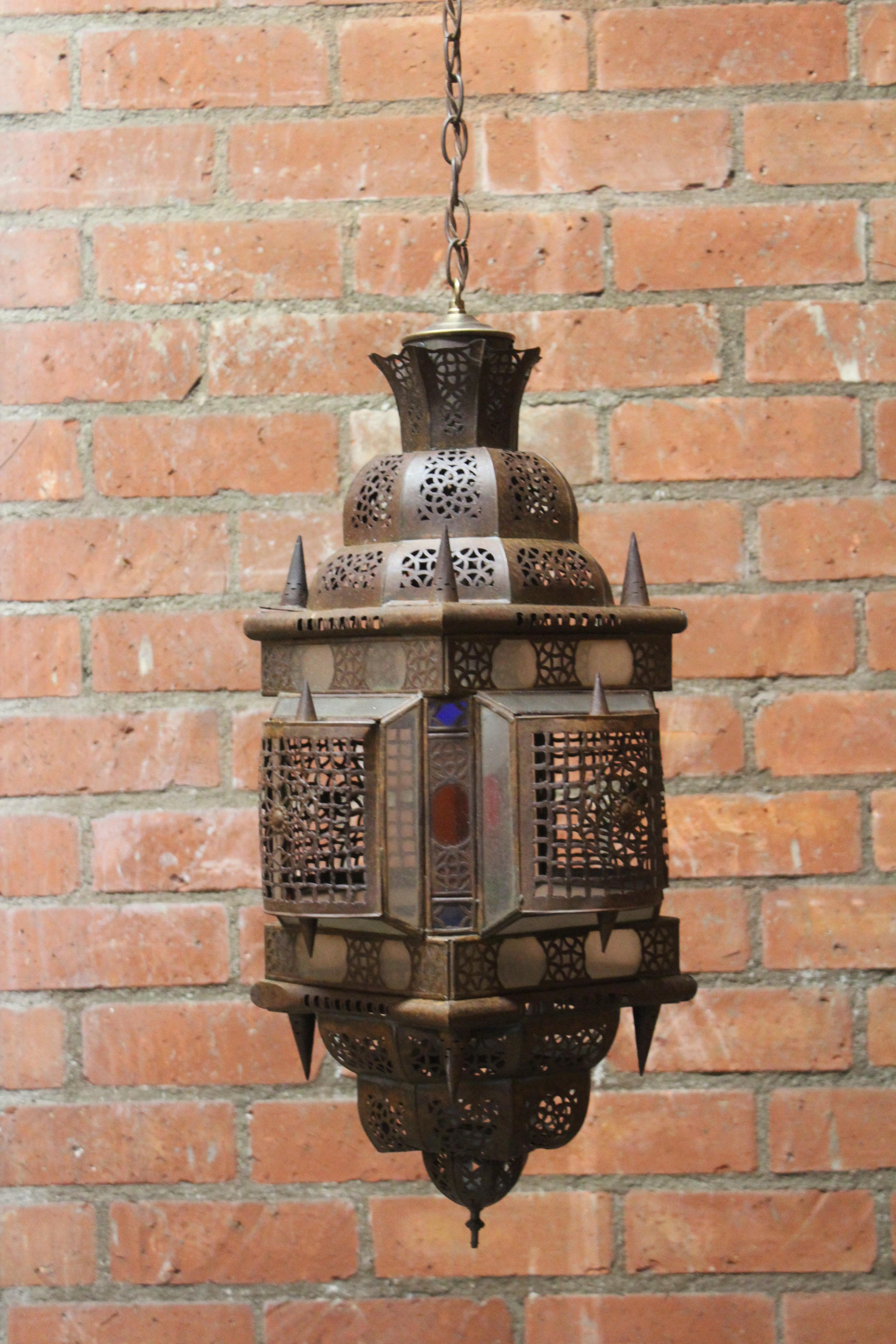 Lampe pendante marocaine vintage. Nouvellement recâblé, et en excellent état avec une patine appropriée à l'âge. Câblé avec une chaîne ancienne. Utilise une seule ampoule standard. En métal avec des découpes. Inserts en verre coloré. longueur totale