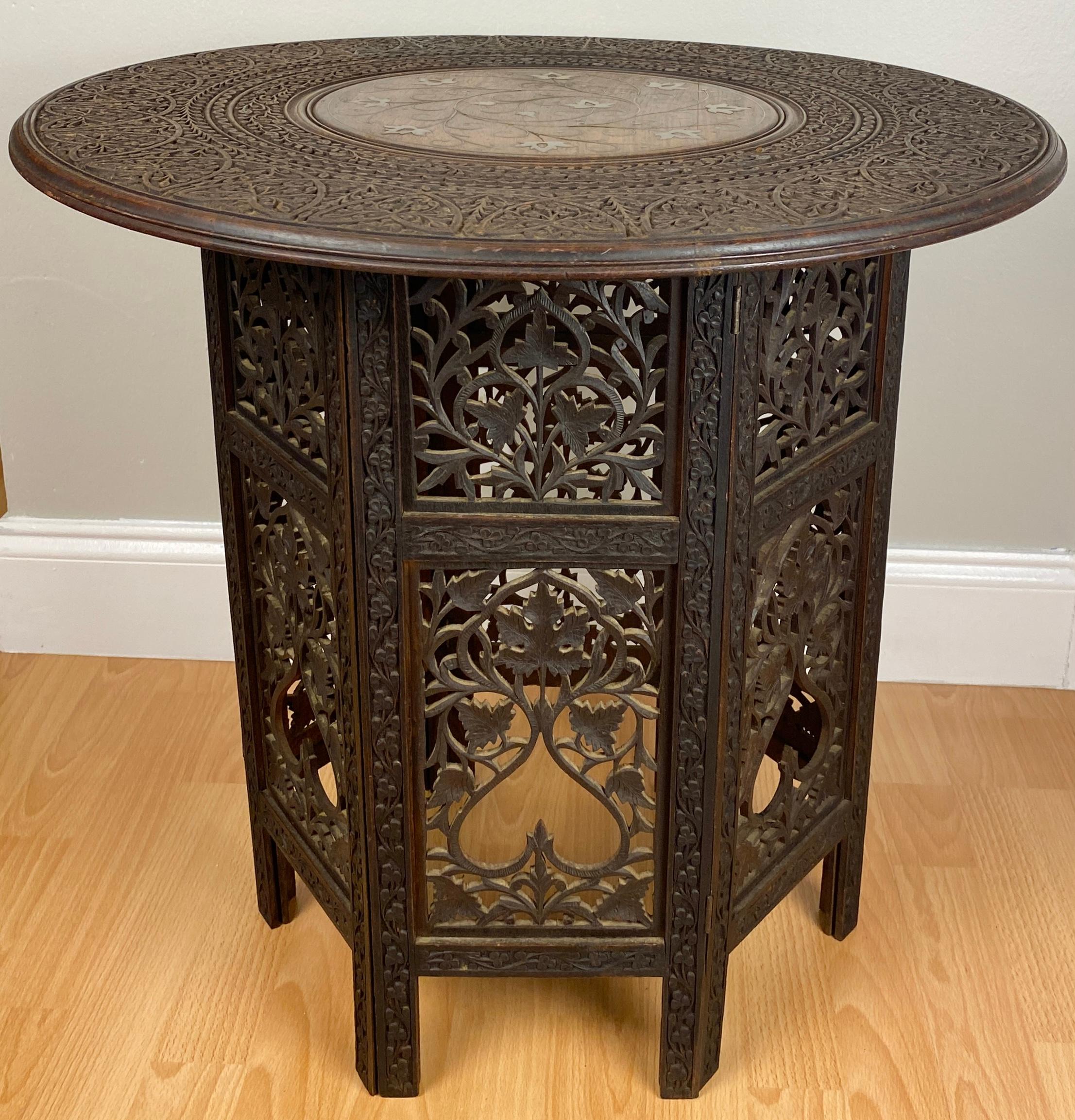 Intricately hand carved, antique Moroccan side table crafted in walnut wood having a round top inlaid with copper floral patterns in the Style of the Ottomans. Highlighted above the six sided base with Moorish arches design that allows the viewer to