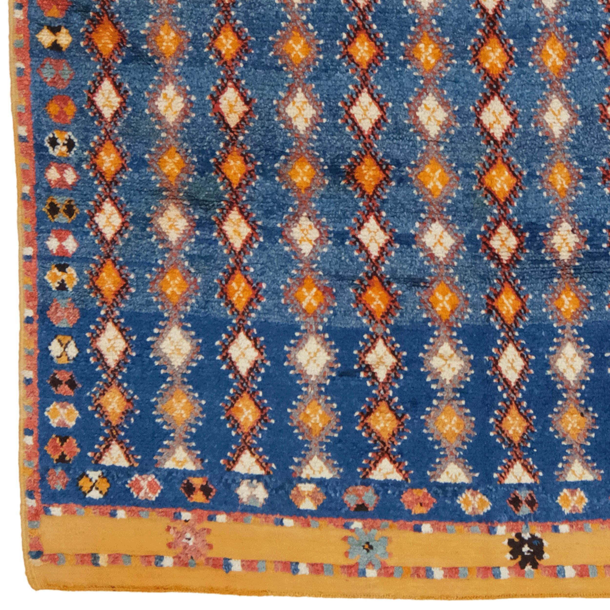Dieser antike Marokko-Teppich aus dem 19. Jahrhundert zeichnet sich durch sein historisches und kulturelles Erbe aus. Diamantformen in gelben, weißen und roten Tönen auf blauem Grund zeugen von Eleganz und handwerklicher Meisterschaft. Die floralen