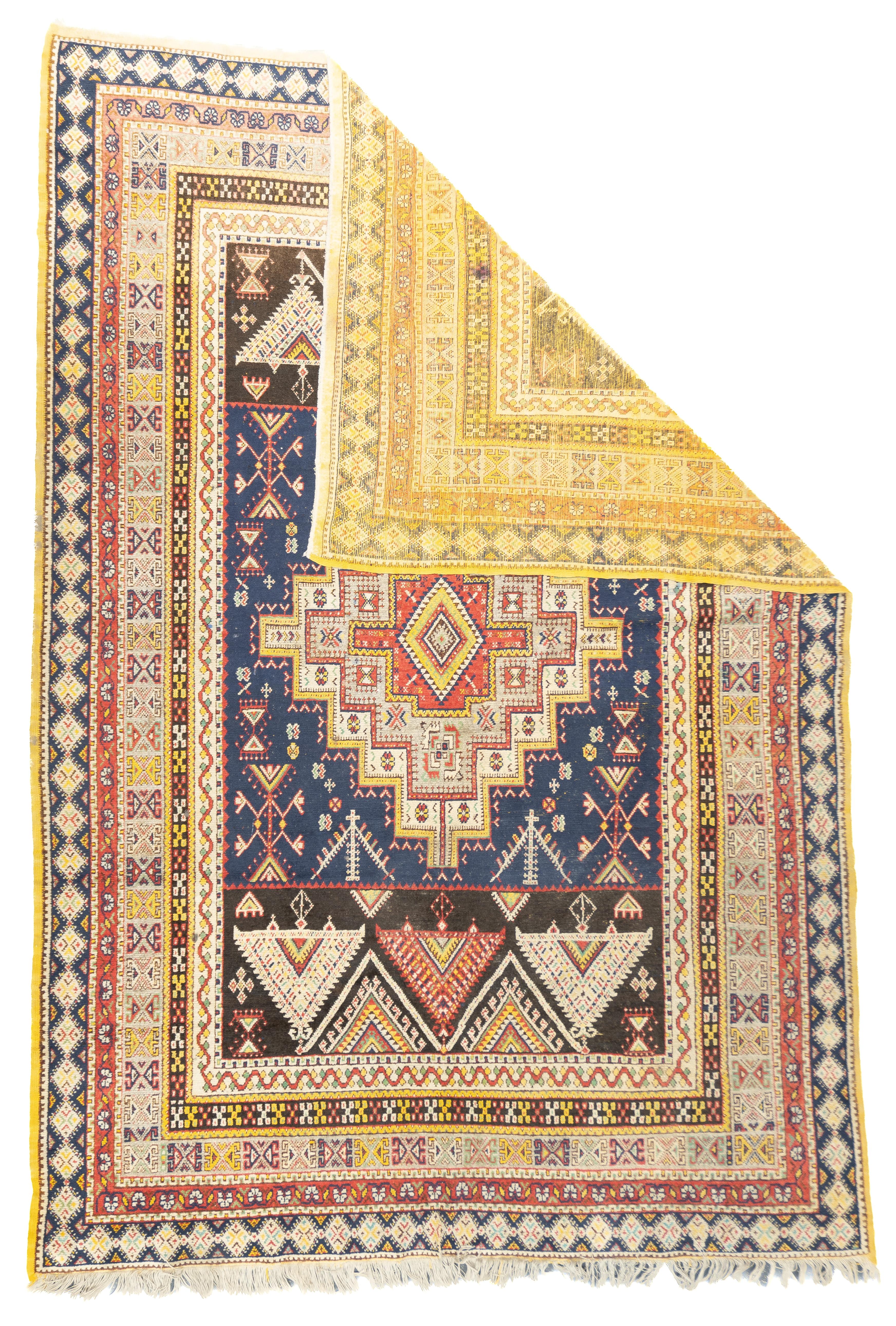 Antique Moroccan Rug 6'9'' x 9'8''. This moderate/coarse, all wool Moroccan piece shows a complex palette,. with a dark blue field centred by a nested ecru, yellow and rust stepped medallion, and a bold zig-zag of triangles above and below. More