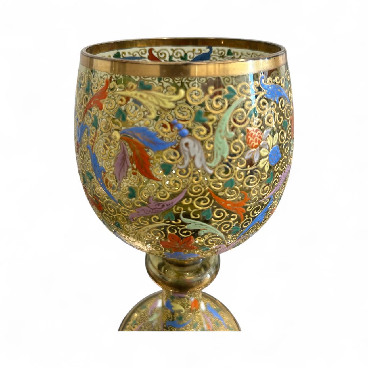 This exquisite antique Moser goblet is a masterful example of Bohemian enamel and gilt glass, showcasing the exceptional artistry and luxurious craftsmanship that define Moser glassware. Standing 11.75 inches tall, this hand-blown crystal chalice