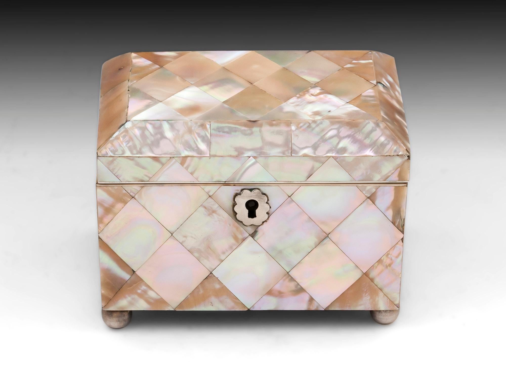 Antique mother-of-pearl tea caddy with a beautiful diamond shaped design with silver ornate shaped escutcheon and standing on four silvered ball feet.

The interior of this small antique mother-of-pearl tea caddy features two compartments with
