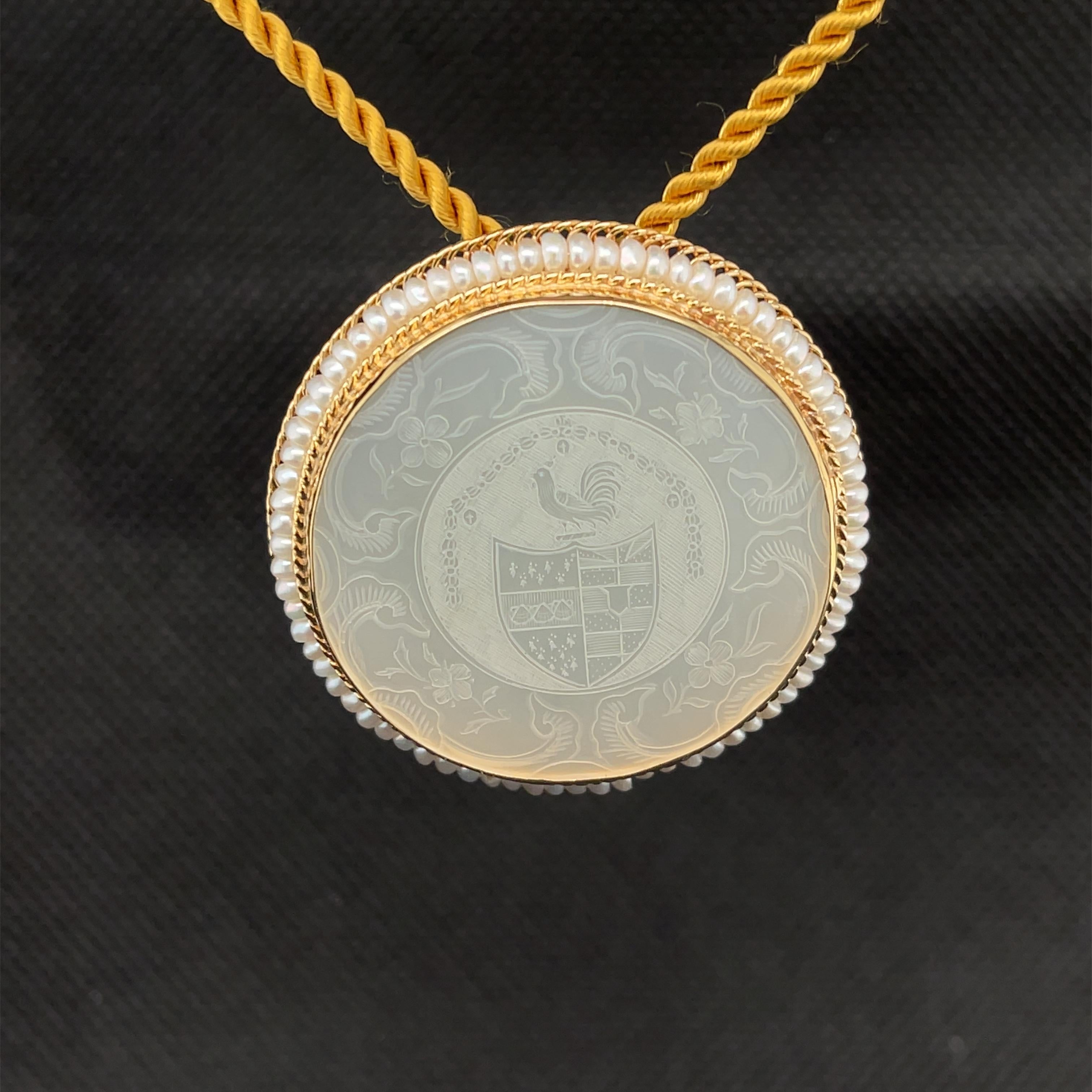 Cette élégante combinaison pendentif / broche présente un compteur de jeu en nacre antique serti en or jaune 14k avec de délicates perles de rocaille. Un blason royal a été sculpté au centre de ce motif et est encadré par une magnifique bordure