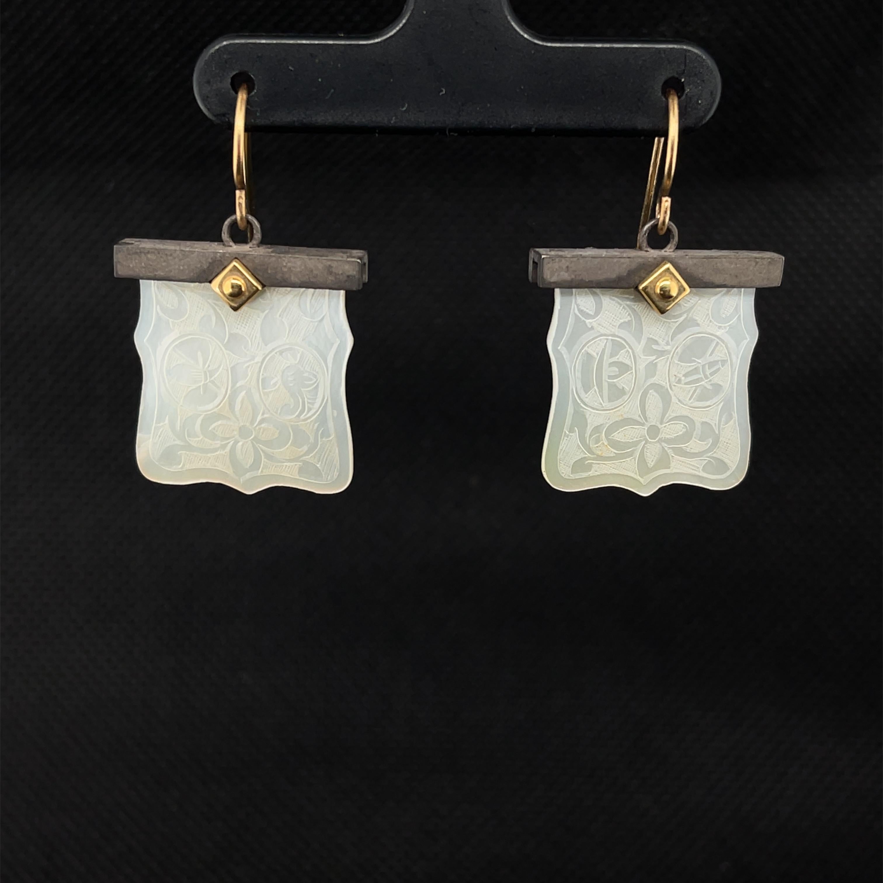 These pretty earrings feature antique, mother-of-pearl Chinese gambling counters dating back to the 18th Century. The square gaming counters with scalloped edges and flowing corners are set in striking blackened silver settings that are accented