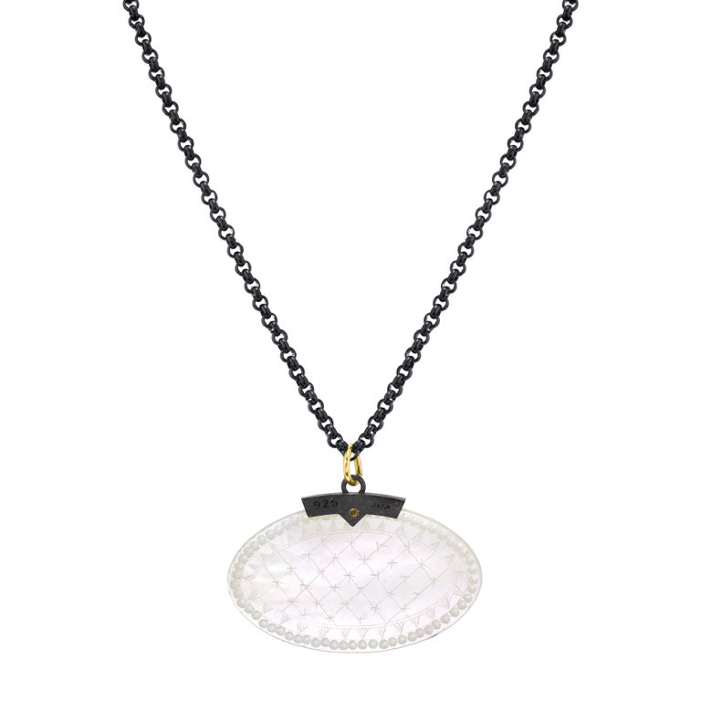 This striking necklace features an antique, mother-of-pearl Chinese gambling counter dating back to the 18th Century. The oval gaming counter is set in a striking blackened silver setting that is accented with an 18k yellow gold rivet and bail. This