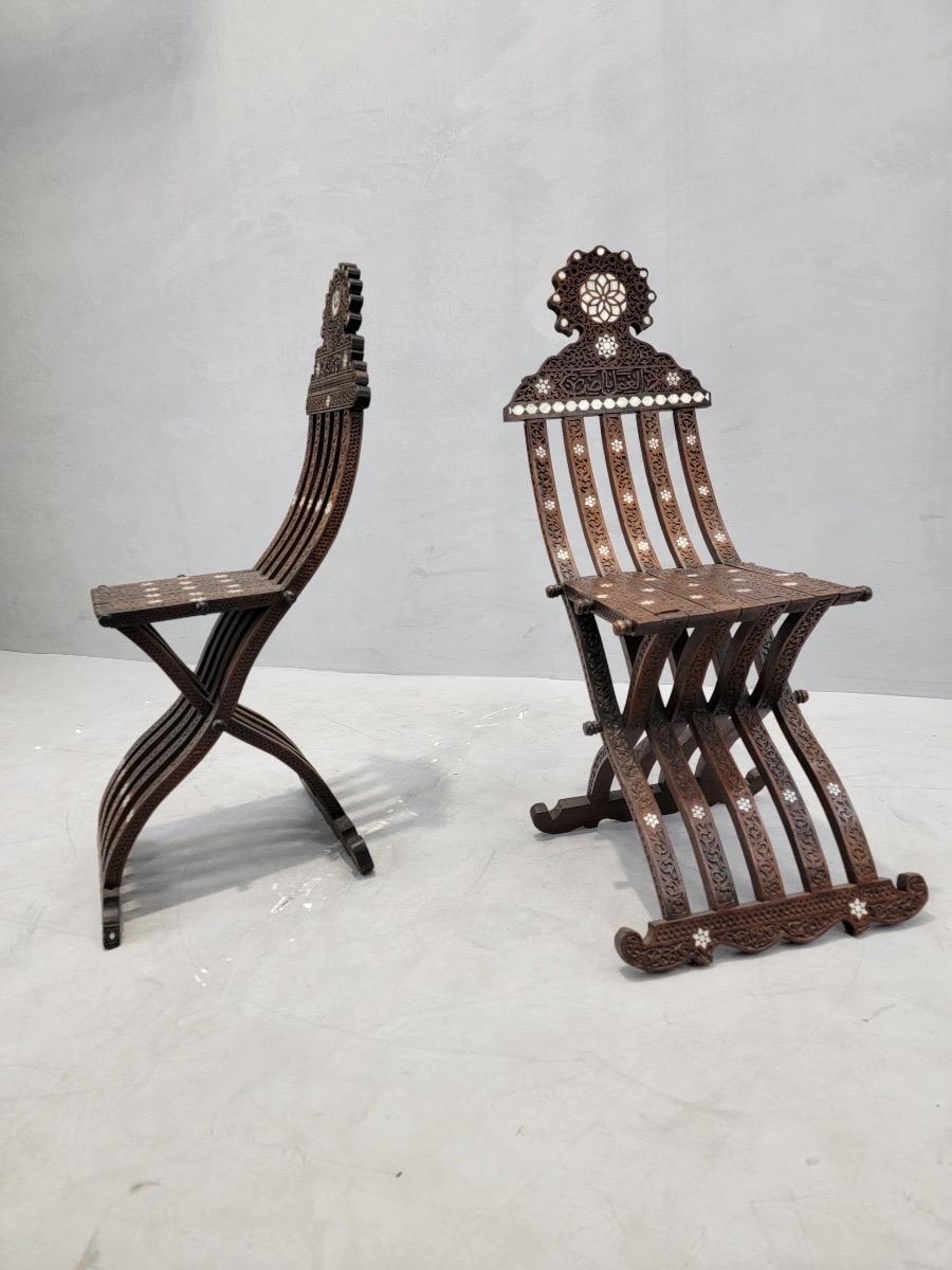 Antique Mother of Pearl Inlaid Folding Middle Eastern Chairs - Set of 2

This pair of 19th century chairs is inlaid with exquisite mother of pearl detailing and incised carvings with Arabic inscriptions in each slat of wood. Use them as seating your