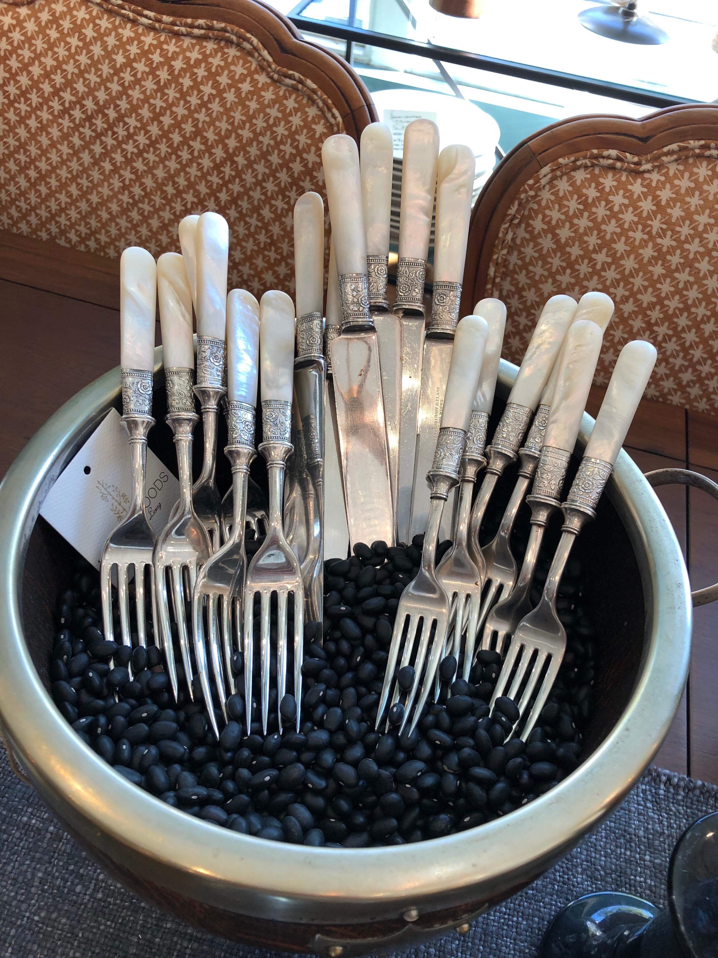 We are loving this elegant set of antique mother of pearl, sterling and silver plate flatware. This set includes knives, dinner forks and dessert forks with beautiful Mother Of Pearl handles and decorative sterling silver band detailing on each