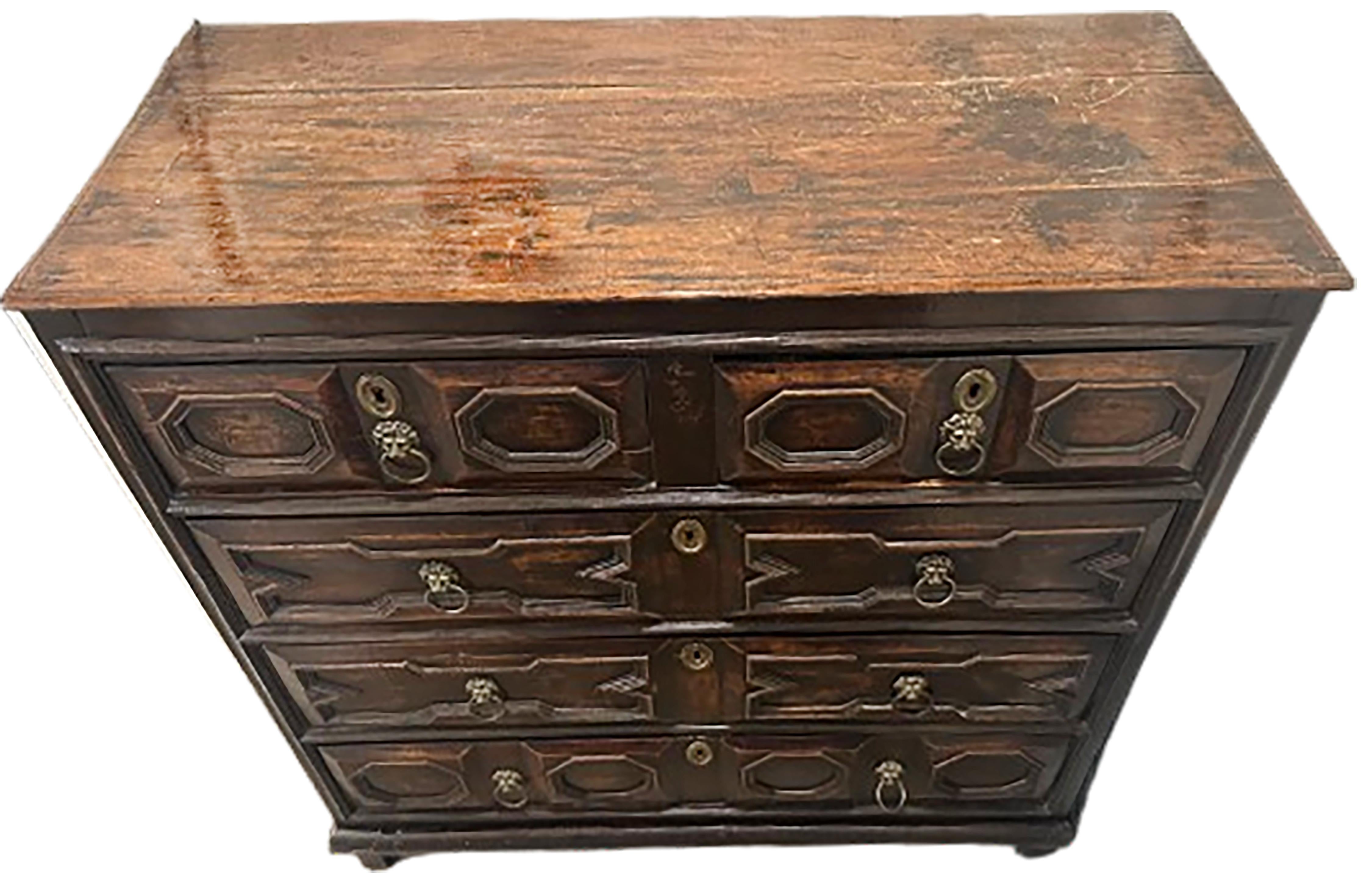 A handsome Jacobean chest of drawers. Four drawers. Made of Oak with lion face brass handles and key-holes. Made in England between the 17th-18th century. Beautiful dark brown finish. 

No obvious markings present on the piece.

In good condition.