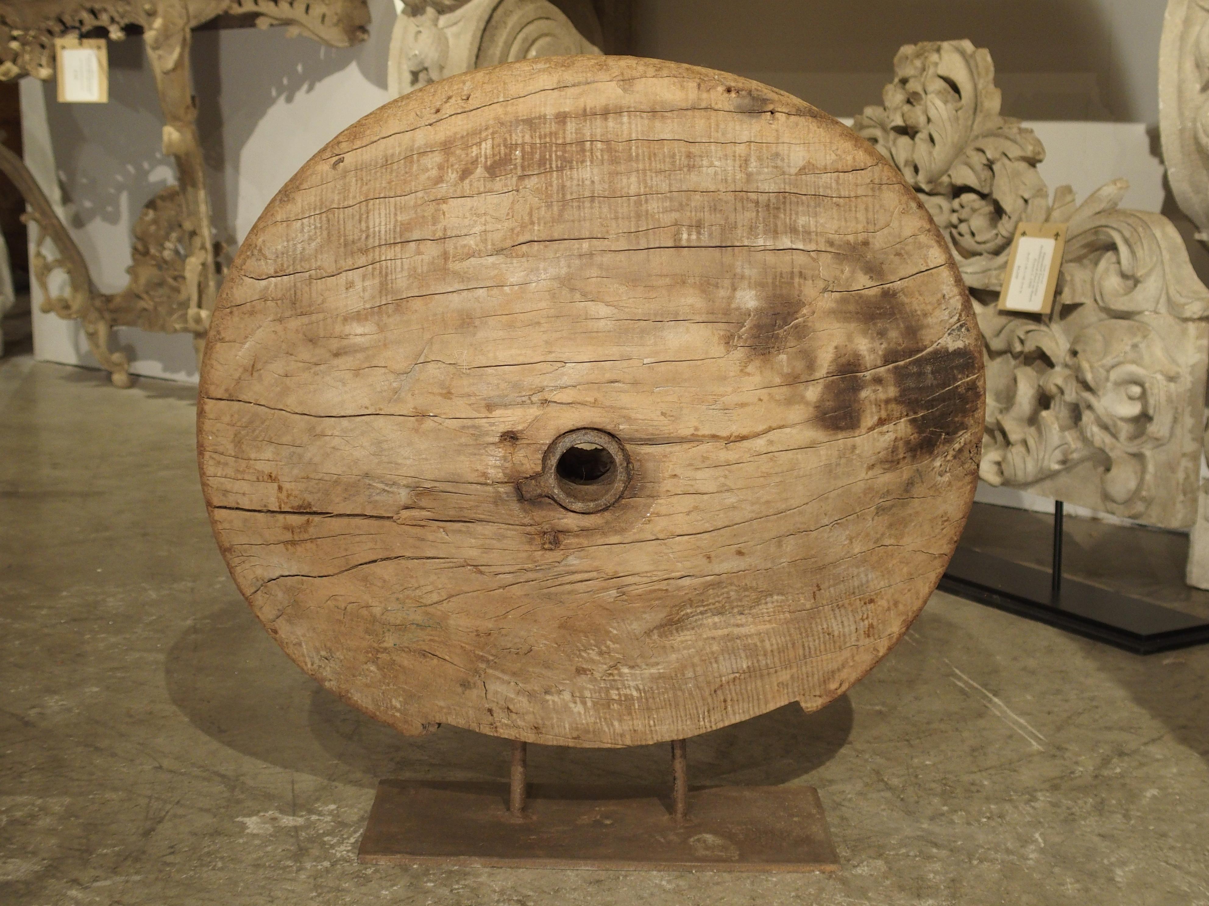 This striking antique wooden work wheel from India has been mounted on a metal stand as a piece of art. It would have been one of two or more wheels on a cart or carriage. Today they are prized as pieces of art and are a wonderful topic of