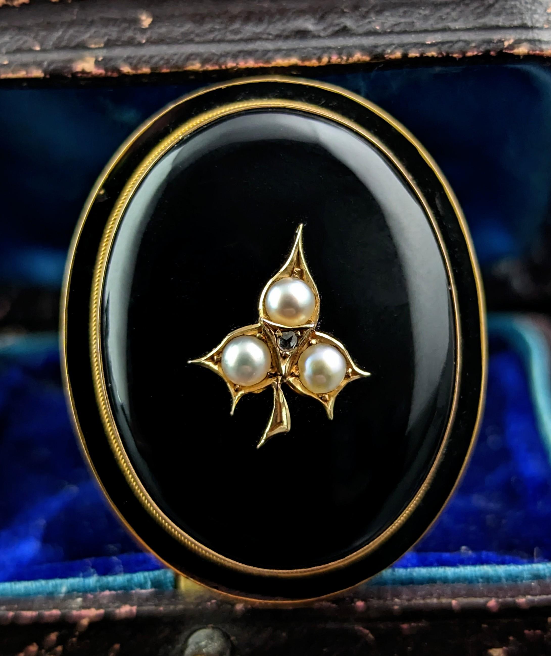 You can't help but be enchanted by this fine antique Mourning brooch.

It is crafted in rich 15ct gold with a large inky black Onyx cabochon to the front, this is mounted with a pretty ivy leaf set with creamy pearls and a diamond point to the