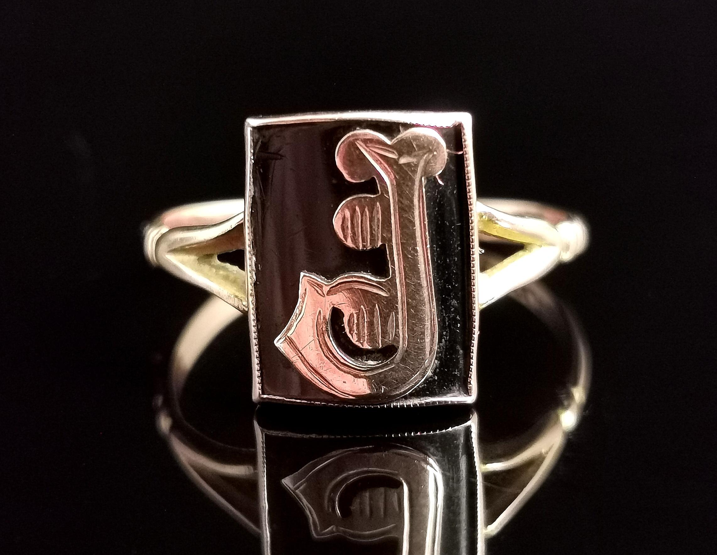 A gorgeous antique, Edwardian era mourning ring.

This is an initial ring with an applied Rose gold letter J, set on a rich black onyx panel.

The ring has decorative split shoulders and a smooth polished band.

This style was popular towards the