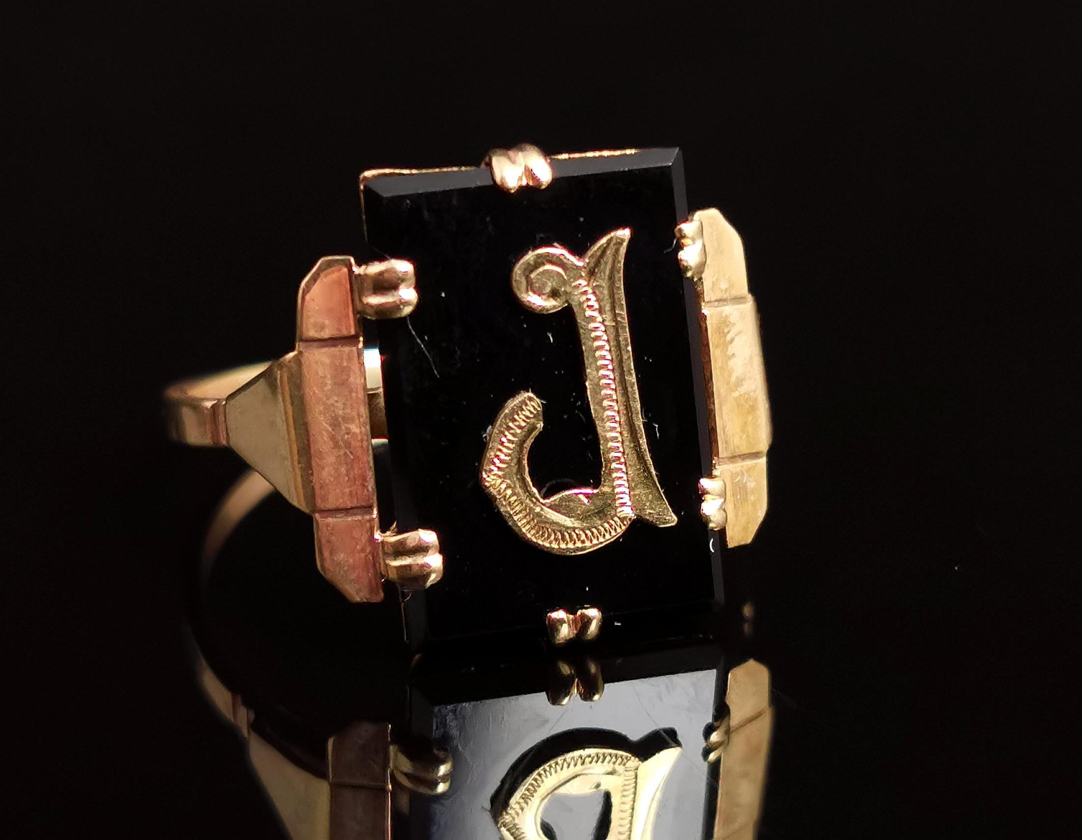 A gorgeous antique, Art Deco era mourning ring.

This is an initial ring with an applied gold letter J, set on a rich black onyx panel.

The ring has decorative stepped shoulders and a slender smooth polished band.

This style was popular towards