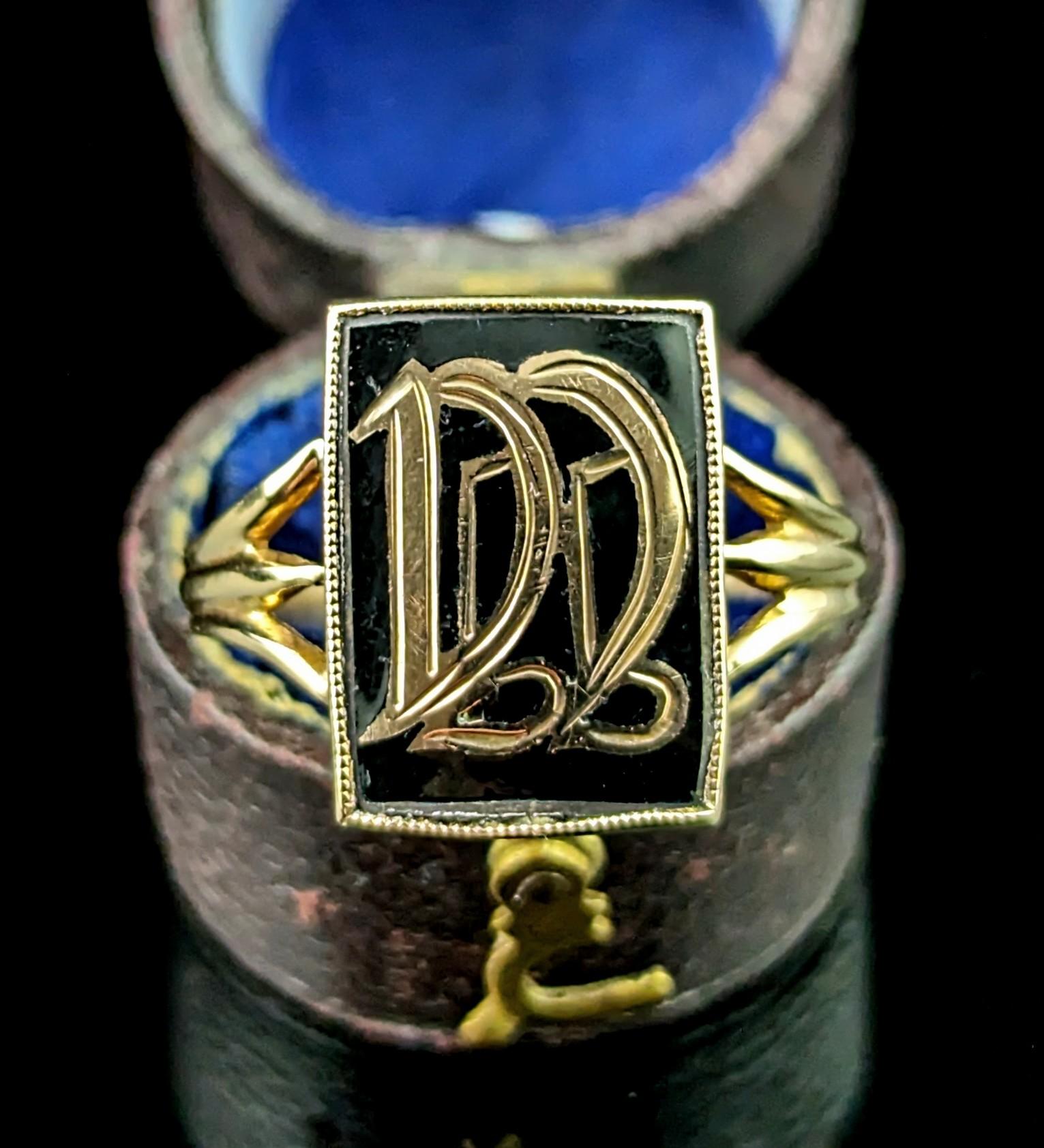 A gorgeous antique, late Victorian era mourning ring.

This is an initial style signet ring with an applied gold monogram of the initials DD, set on a rich black enamel panel and set into a gold millegrain edge bezel frame.

The ring has decorative