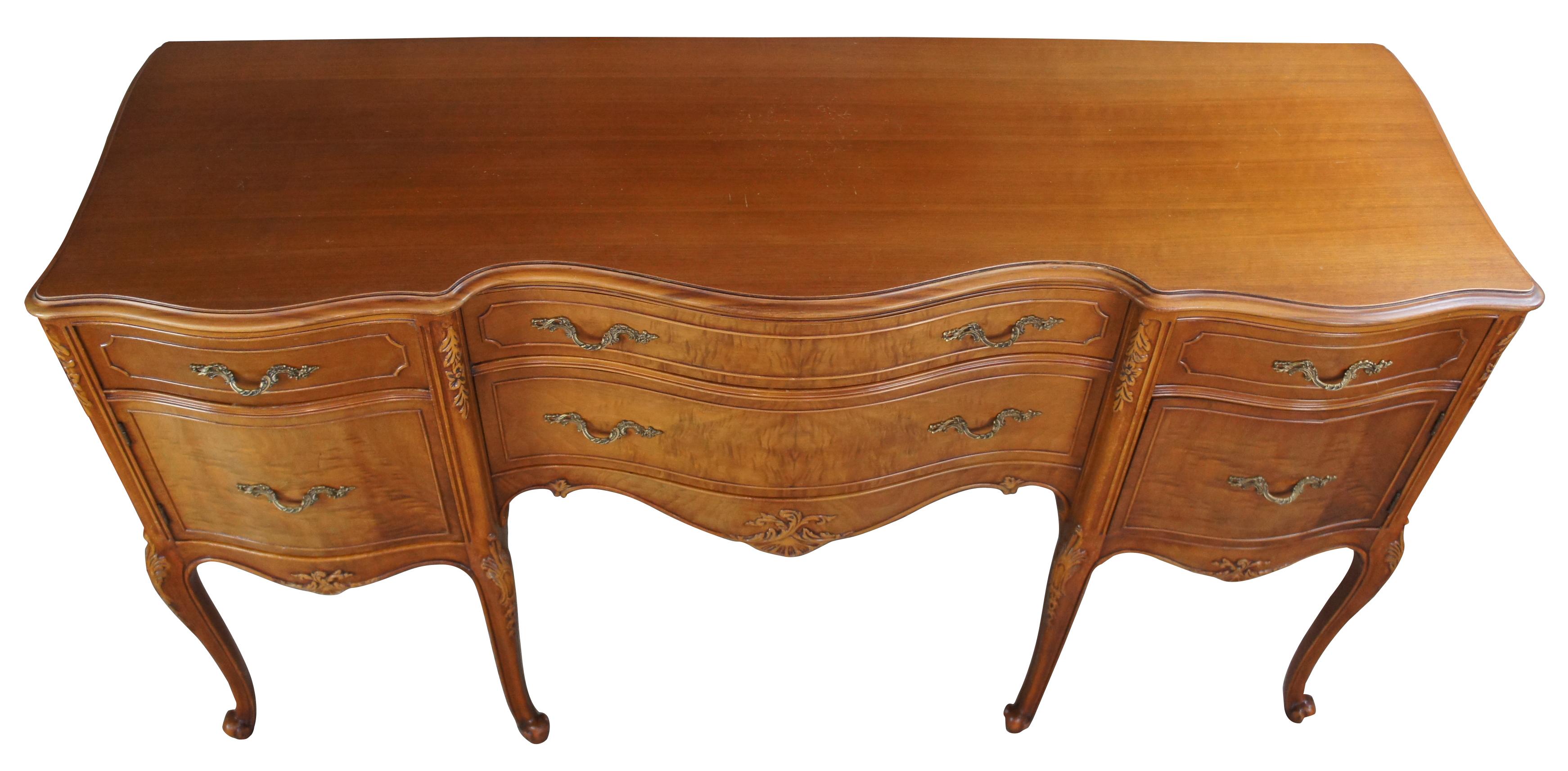 Mt. Airy buffett. Made from walnut with a serpentine top and crotch veneered drawers, circa 1940s . Features carved accents, brass hardware and long cabriole legs. Includes four drawers and two cabinets.