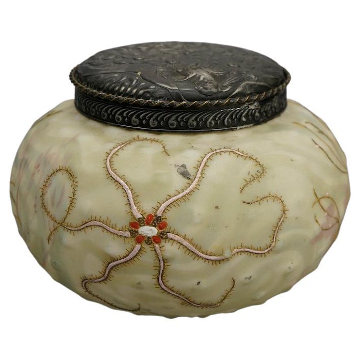 An antique Mt Washington Crown Milano seascape biscuit or dresser jar offers art glass construction  in bulbous form and decorated in hand enameled and jeweled starfish,  floral embossed silver plate lid, c1890

Measures- 6''H x 7.75''W x 7.75''D

