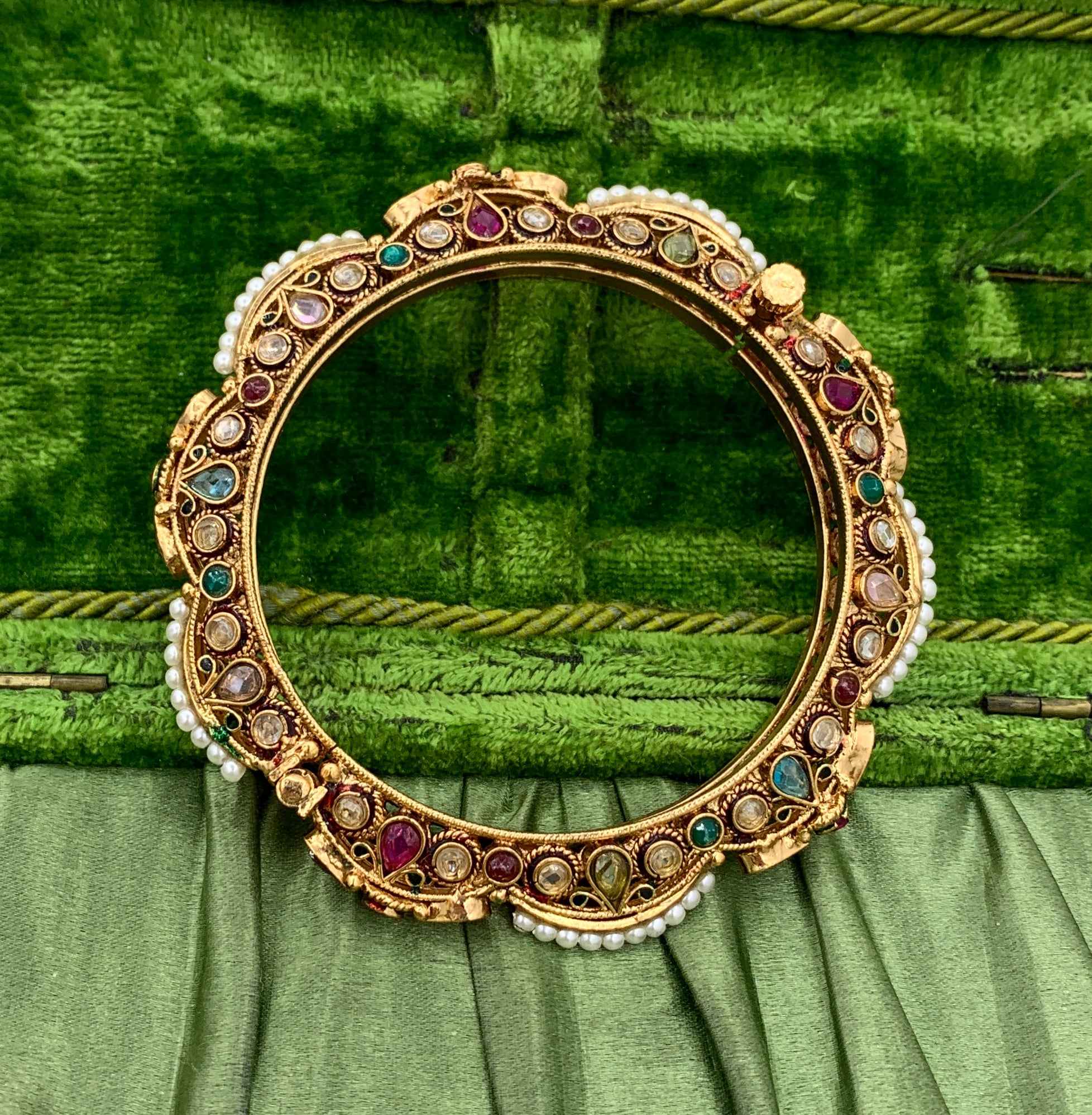 Ce magnifique By Design Jewelers indien ancien est orné de rubis, d'émeraudes, de péridots, de topazes et de perles, dans un style classique du Rajasthan moghol.  Le bracelet est doré à l'or fin 10 carats.  C'est tout simplement exquis.  Le bijou
