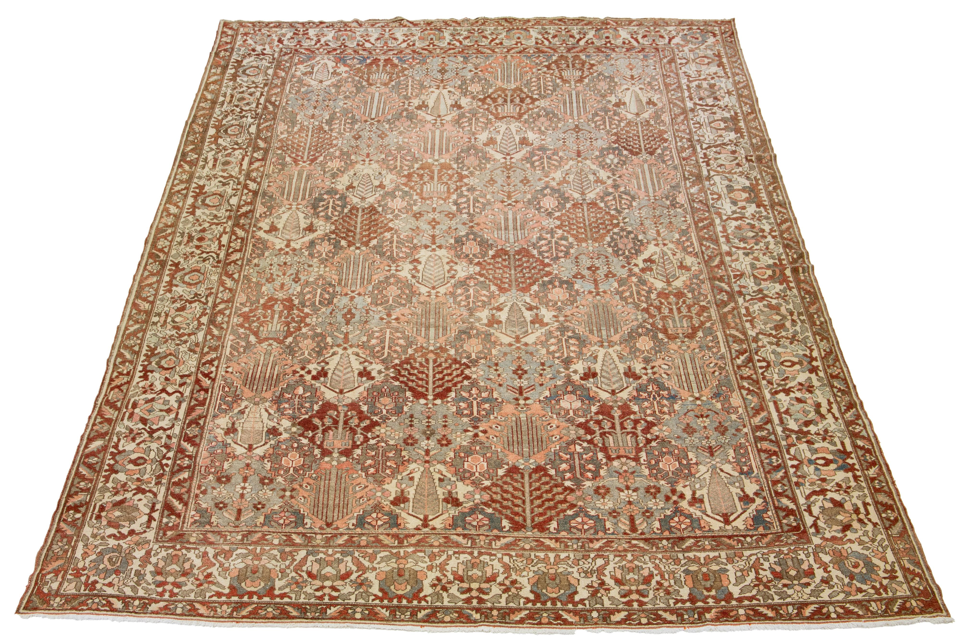 Beautiful Antique Bakhtiari hand-knotted wool rug with a gray, red-rust, beige, and pink color field. This Persian piece has an all-over geometric floral design.

This rug measures 13'1