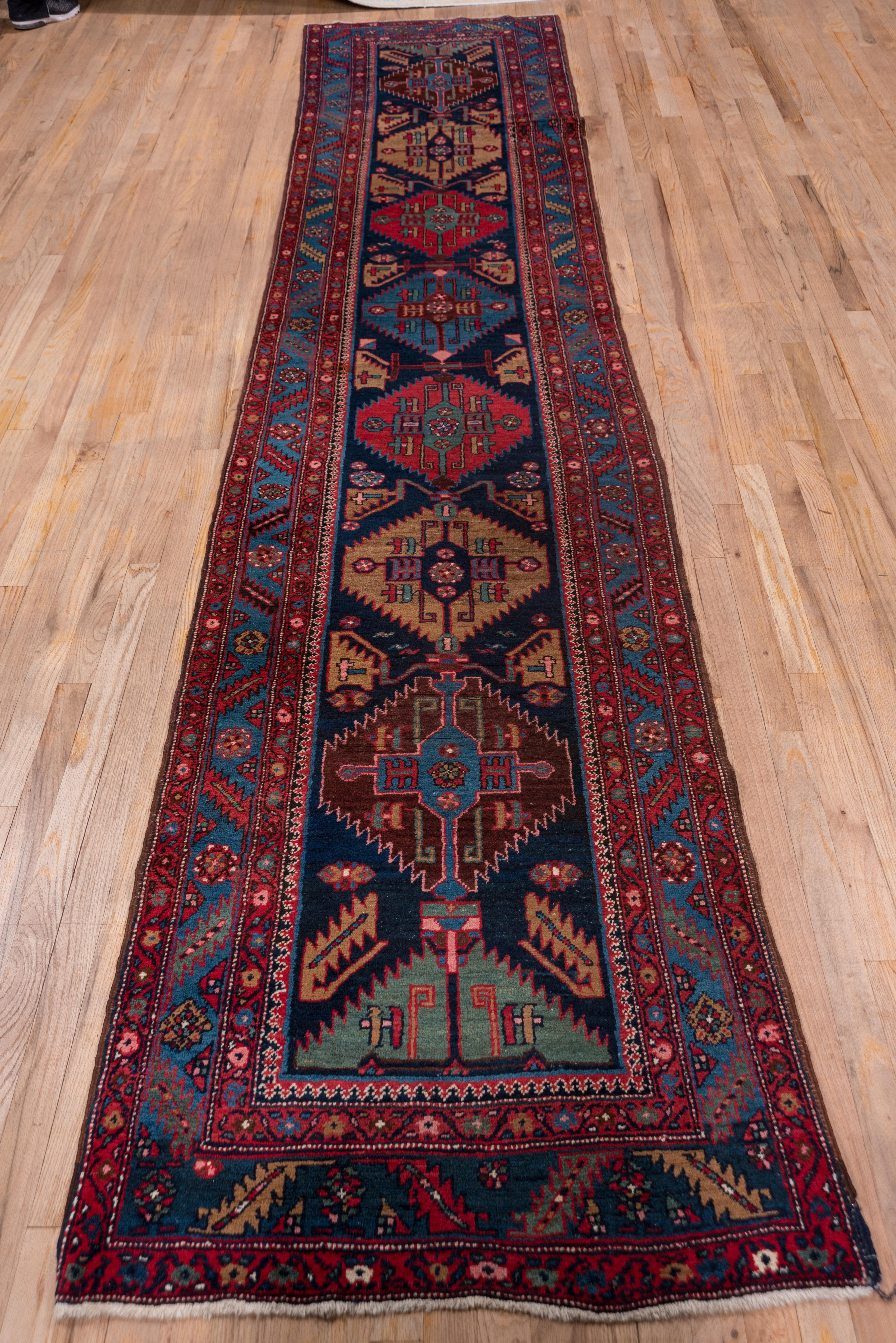 This very well preserved NW Persian village runner features a dark blue field with a serrated hexagon vertically repeating pattern in red, camel, brown, medium green and medium blue. This pattern, now a pole medallion, originally appeared as a