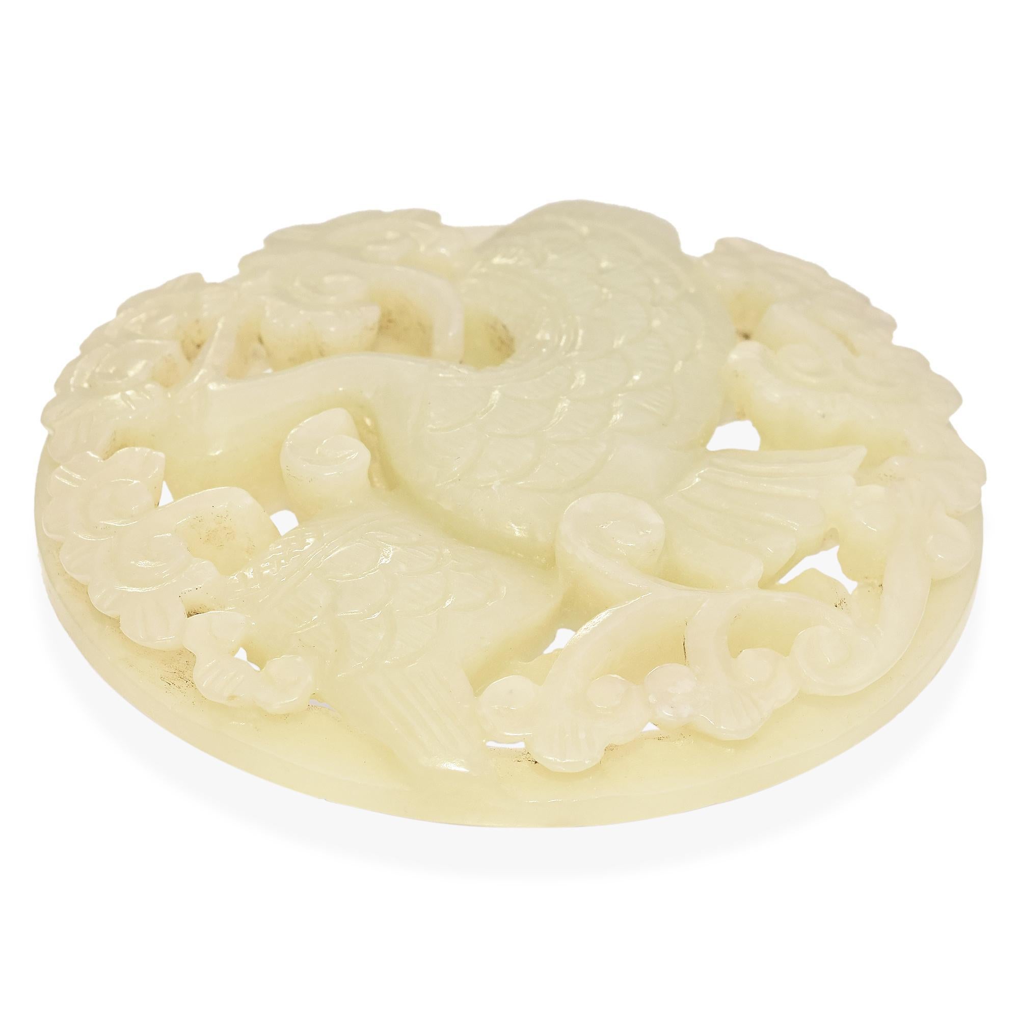 This stunning antique mutton fat jade amulet plaque showcases masterful craftsmanship with an intricate, openwork design featuring a gracefully carved crane amid floral motifs. The highly translucent jade exhibits a rich, creamy-white hue with a