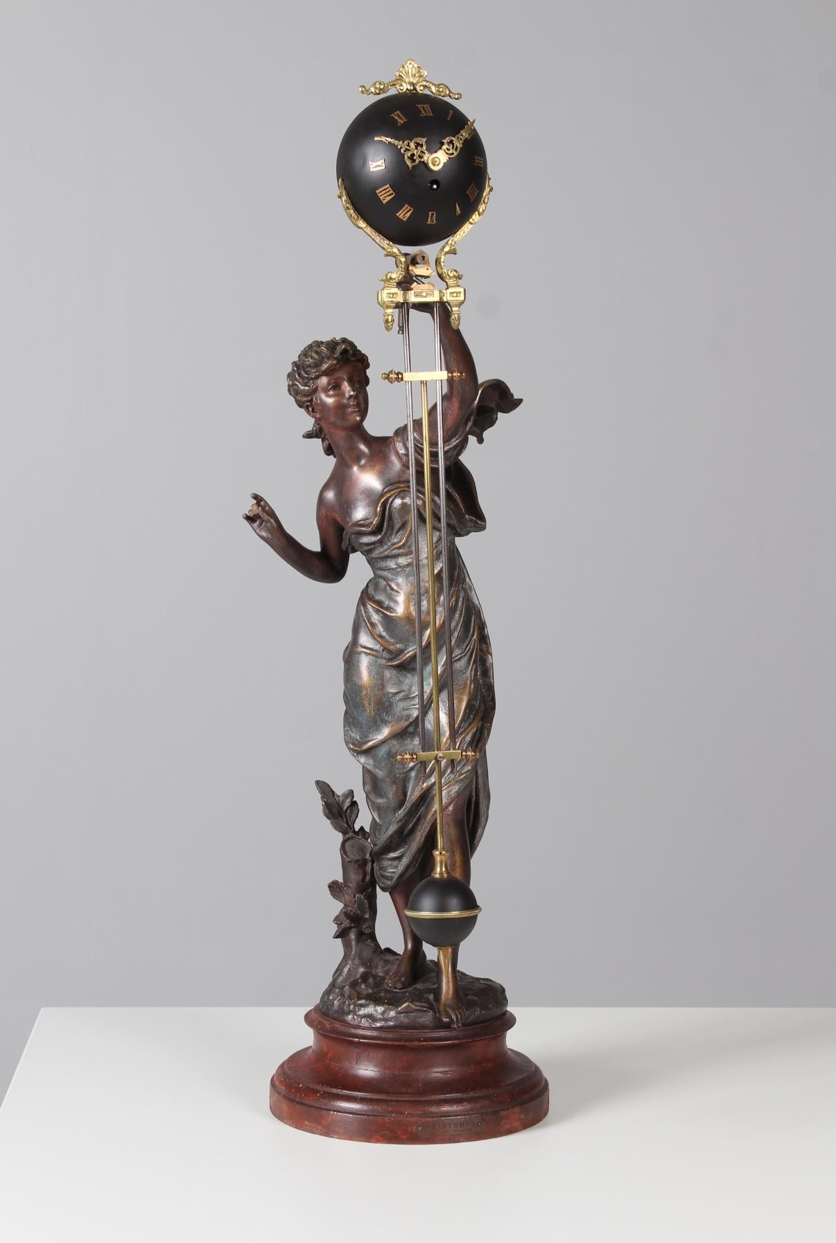 Seltene antike Kaminsimsuhr, sogenannte Mysterieuse Pendule oder Mystery Clock.
Maße: Höhe: 80 cm, Durchmesser: 22 cm.
Auf einem marmorierten Holzsockel steht die weibliche Figur, die die Uhr trägt. In der oberen Kugel befindet sich das Uhrwerk