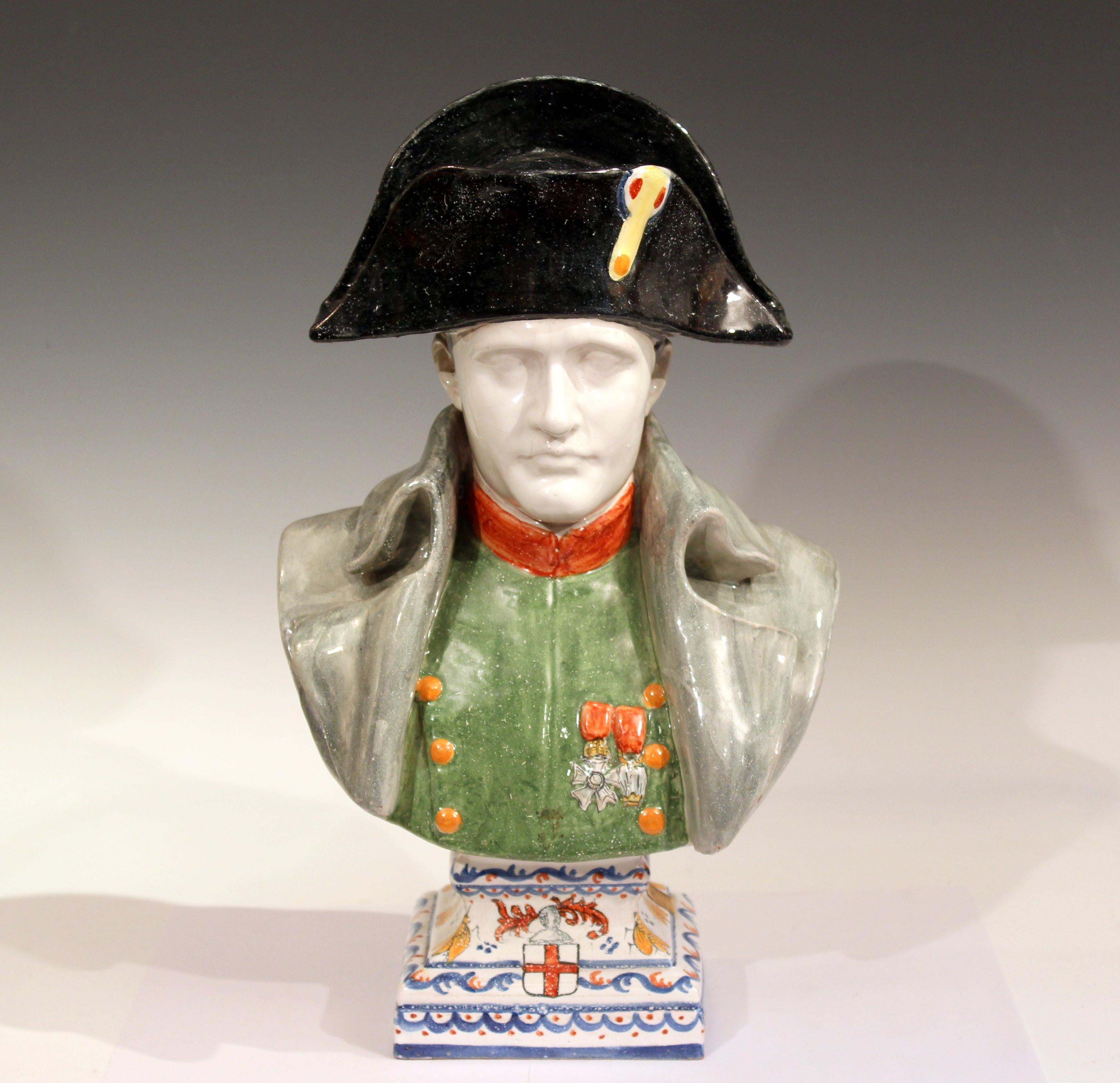 Large antique French faience pottery bust of Napoleon Bonaparte by Alcide Chaumeil, circa late 19th century. Depicting Napoleon in a black hat with gray overcoat over a green uniform with two medals at the breast. The base decorated with a heraldic