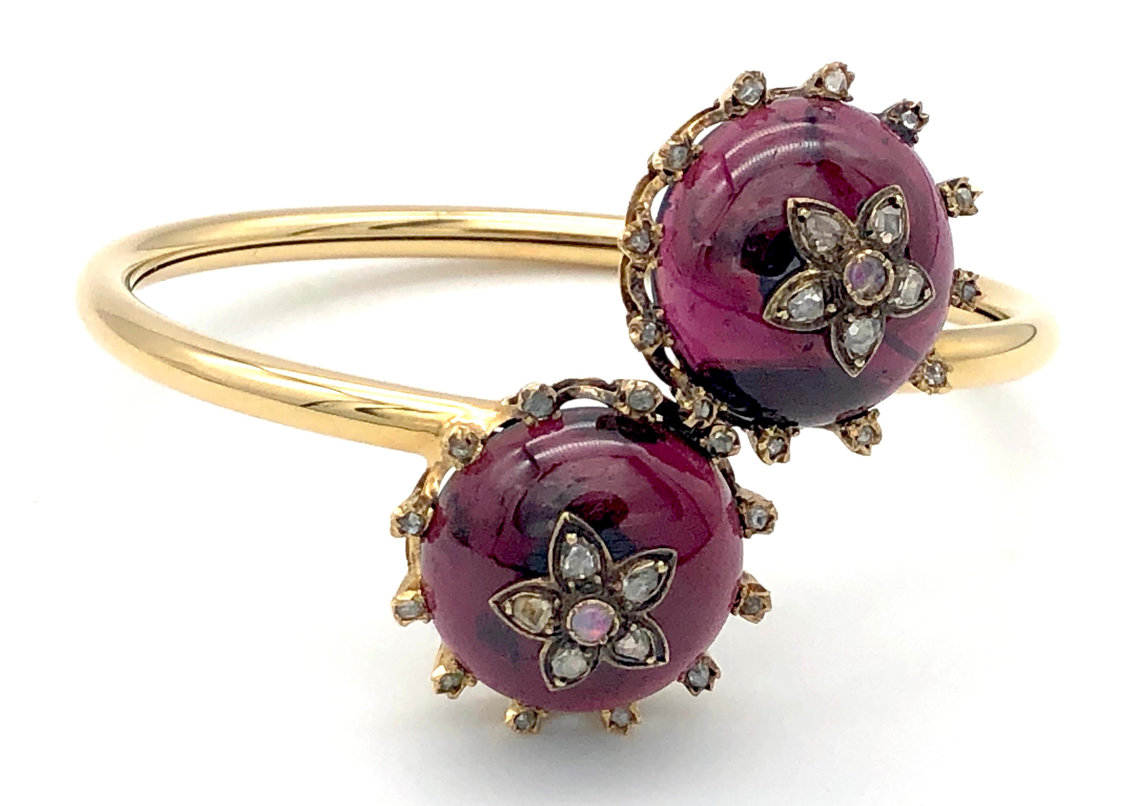 Two magnificent cabochon almandine garnets are mounted in settings reminiscent of crowns with twelve diamond set points.  Each almandin is embellished with a flower set with five rose diamonds and an opal in it's centre.
The cabochons have been