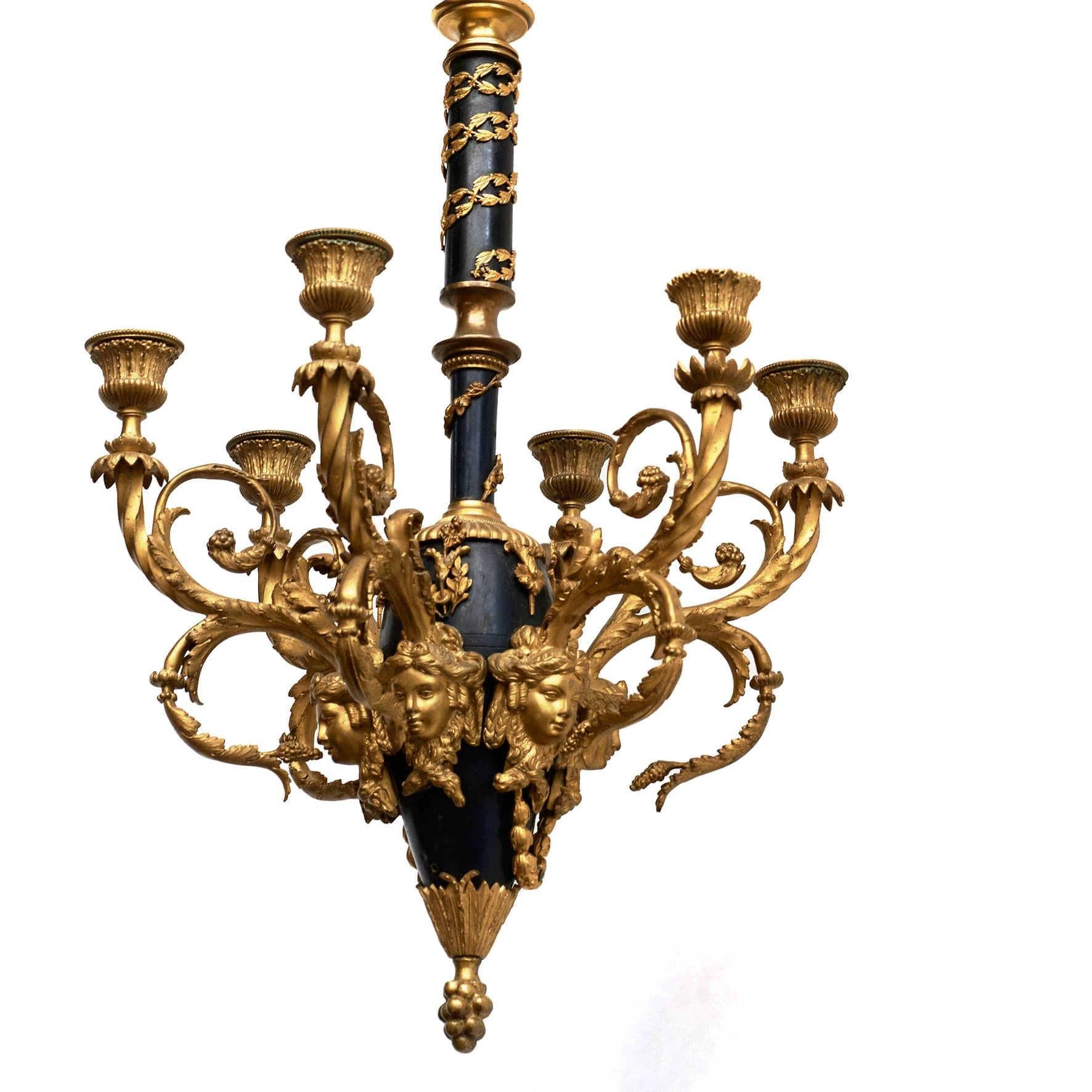 Decorative Napoleon III chandelier with 6 arms.
Gilded in black patinated bronze with fine details, leaf work and gilded female heads under each candle arm and fine chisels on the candle cuffs.

The chandelier is finished with a gilded cone and