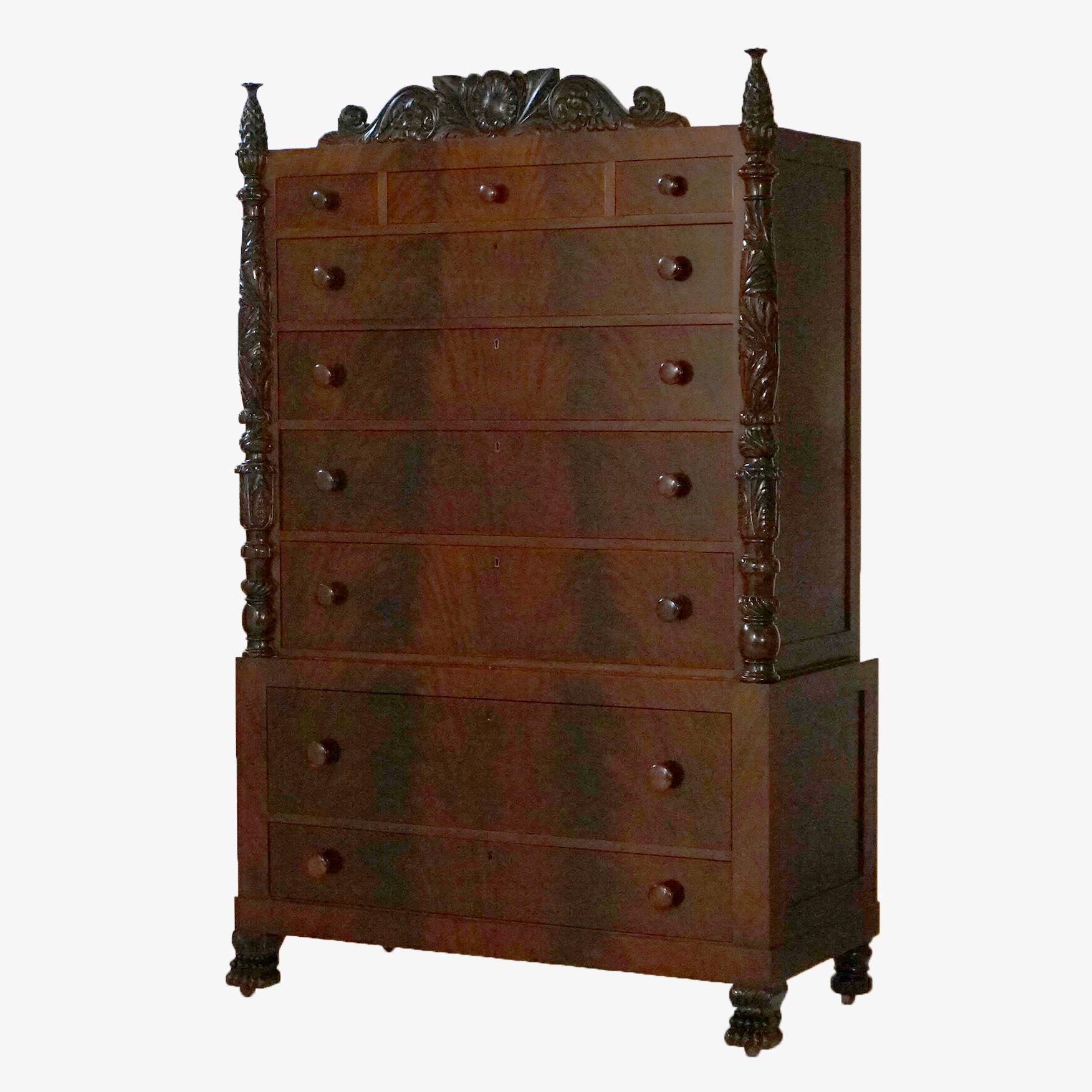 An antique Napoleon III style tall chest of drawers by Berkey and Gay offers flame mahogany construction with foliate carved crest over case with three small drawers over graduated long drawers, flanking foliate carved columns, raised on stylized