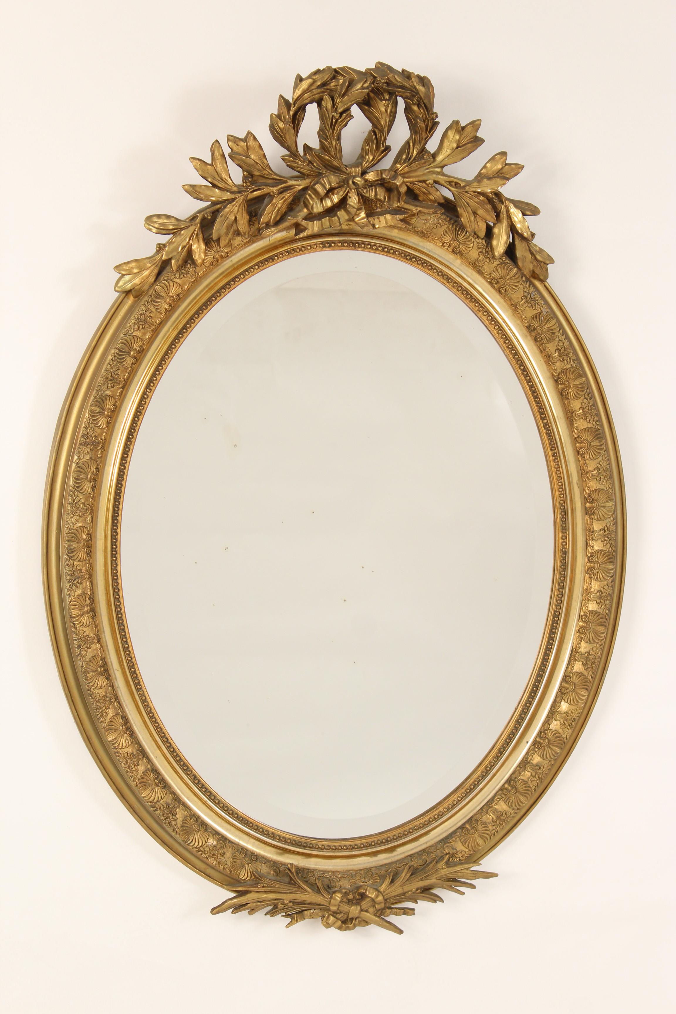 Antique Napoleon III style oval gilt wood and gesso beveled glass mirror, circa 1890-1910.