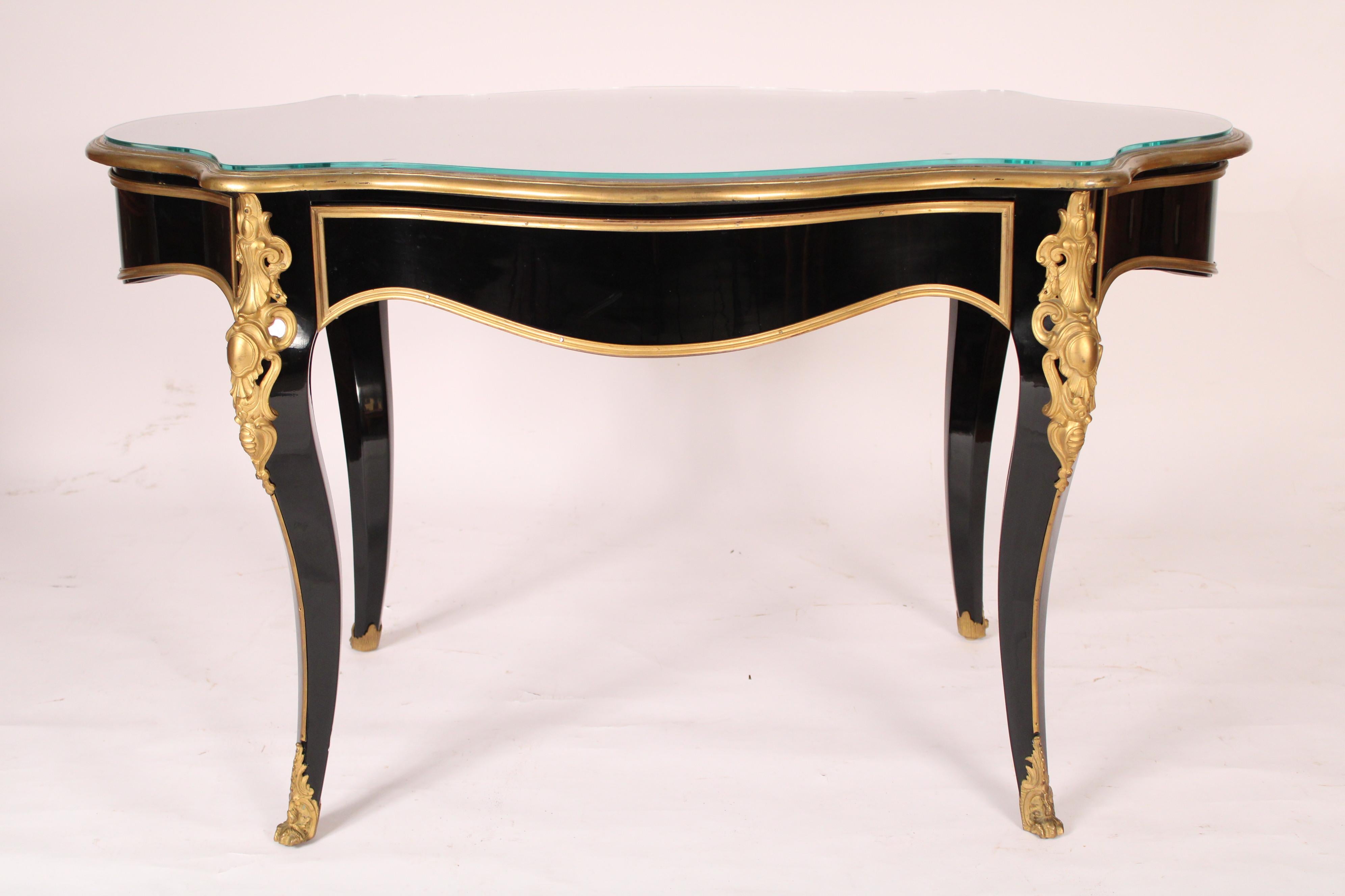 Ancienne table d'écriture de style Napoléon III en laque noire et bronze doré, fin du 19ème siècle. Avec un plateau en laque noire bordé de bronze doré et un plateau en verre plus tardif, un tiroir en frise sur un côté, reposant sur des pieds