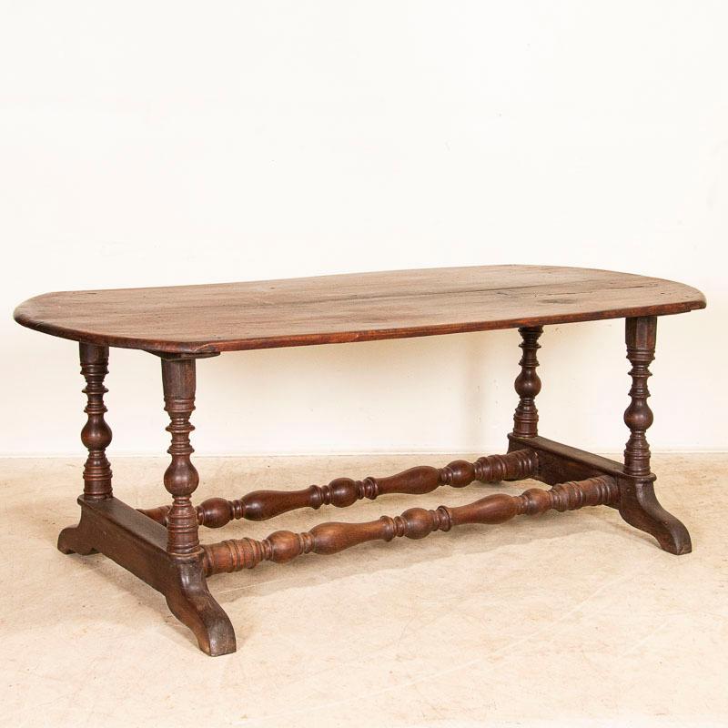 This handsome table reveals it Spanish Colonial style in the turned legs, trestle stretchers, rounded ends and carved feet. It is the beautiful narra wood from the Philippines that draws ones attention to the dark patina and smooth, worn finish.
