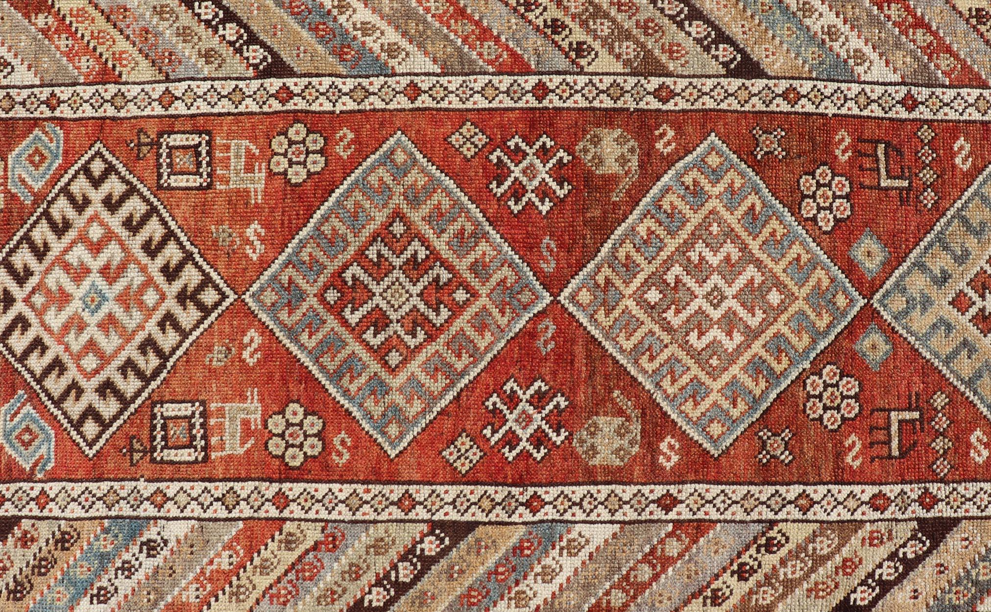 This antique Persian Kurdish runner has been hand-knotted in wool and features a sub-geometric medallion design rendered in multicolor. A complementary, multi-tiered border encompasses the entirety of the piece; making it a marvelous fit for a wide