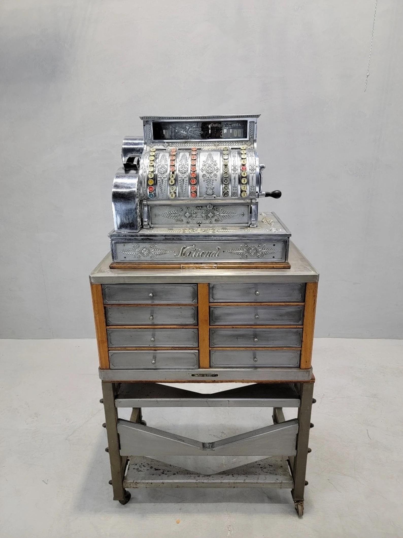 Antique National Cash Register on Custom Antique Industrial Self Standing Cash Drawer Tower

Made by National, this commercial cash register is beautifully decorated with flower and vine motifs. The buttons on the register are functioning, yet some