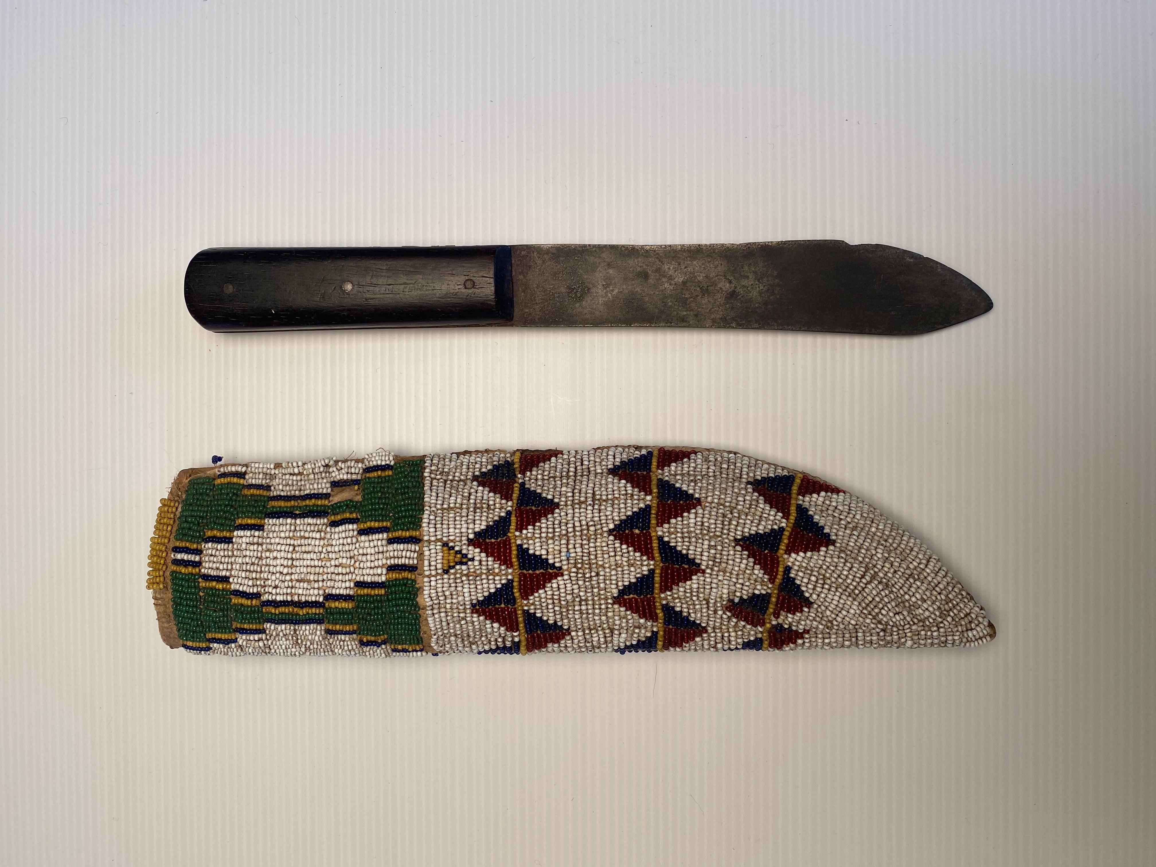 Knife and knife sheath
Fully beaded in Classic Cheyenne geometric design on both sides. Beads are sinew sewn on native tanned deer hide. Sheath has rawhide buffalo liner. Sheath includes period knife with steel blade and hardwood handle with three