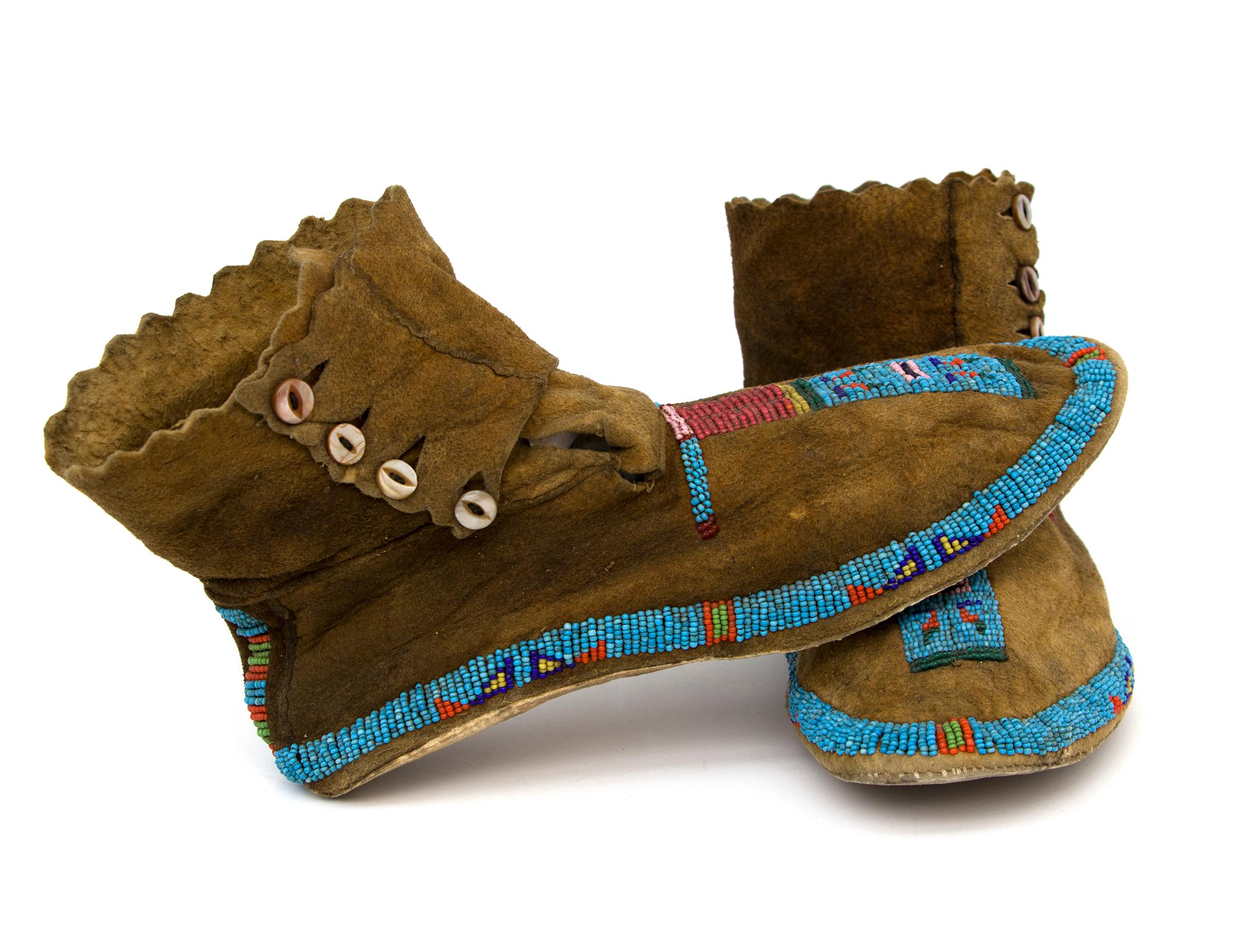 Pair of 19th century Blackfeet beaded hide Moccasins, vintage circa 1890 Native American/North American Indian. The hide is partially beaded in traditional designs with blue, red, yellow, green and pink trade beads. Cuff have a serrated edge and