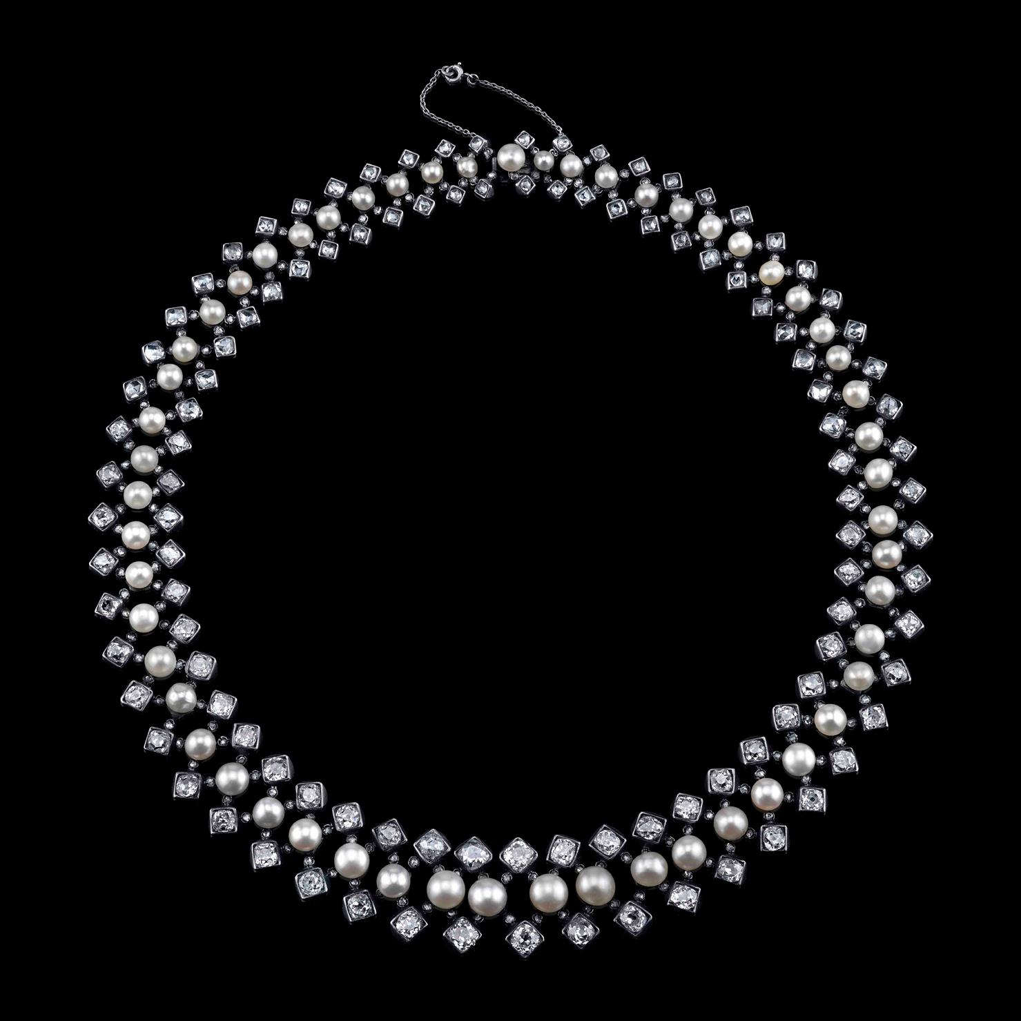 Hand cut old-mine diamonds set in gold and silver.
The middle line set with 55 graduated button-shaped natural pearls, approximately 3.6mm to 6.6 mm, flanked by 2 lines of graduated circular-cut diamonds, weighing approximately 23 carats. 41 cm in