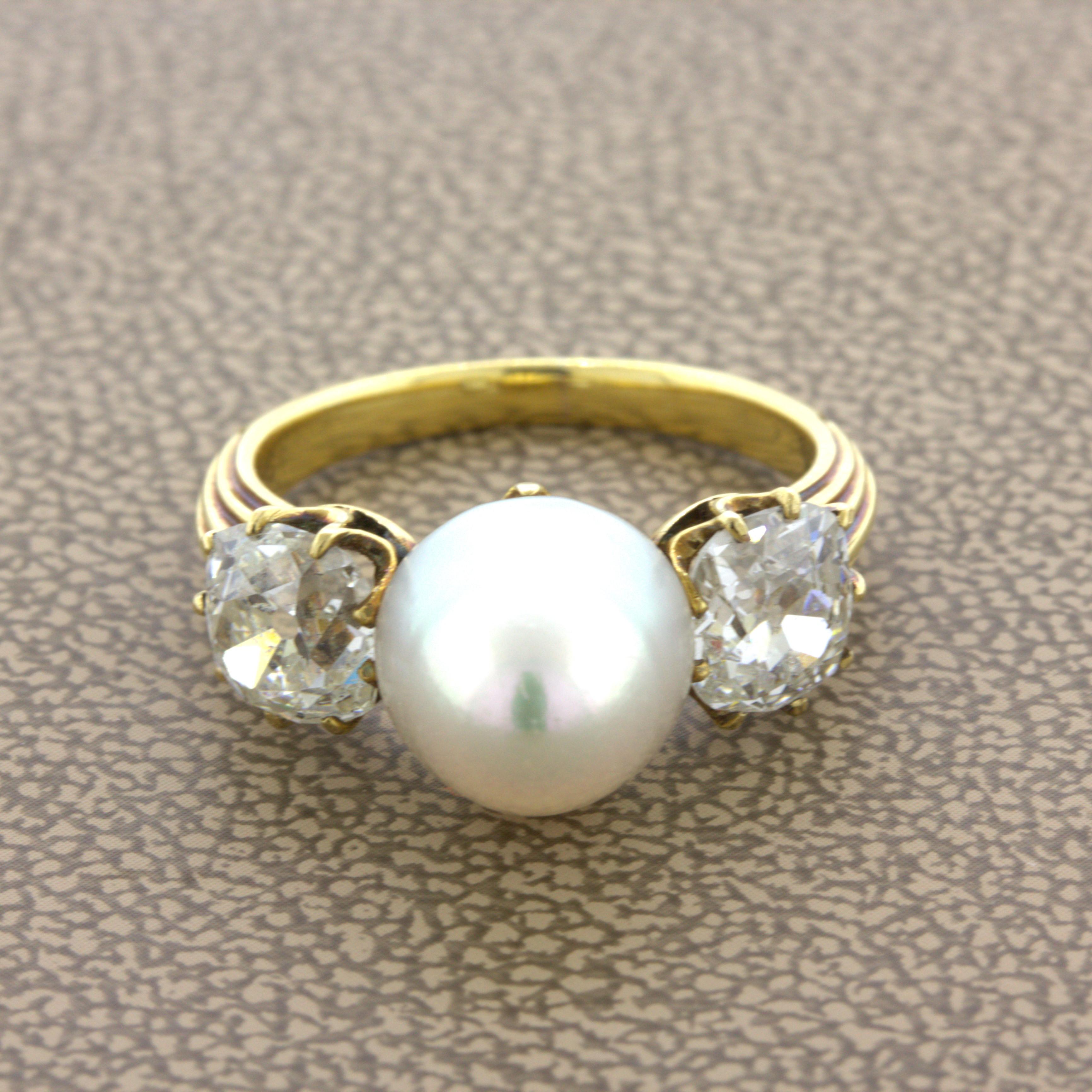 Una perla naturale d'acqua salata di 8,85 mm è al centro di questo anello in oro antico. La perla ha una forma simmetrica unica, con un'eccellente lucentezza e una sfumatura rosa tenue che brilla alla luce. È completato da due diamanti antichi a
