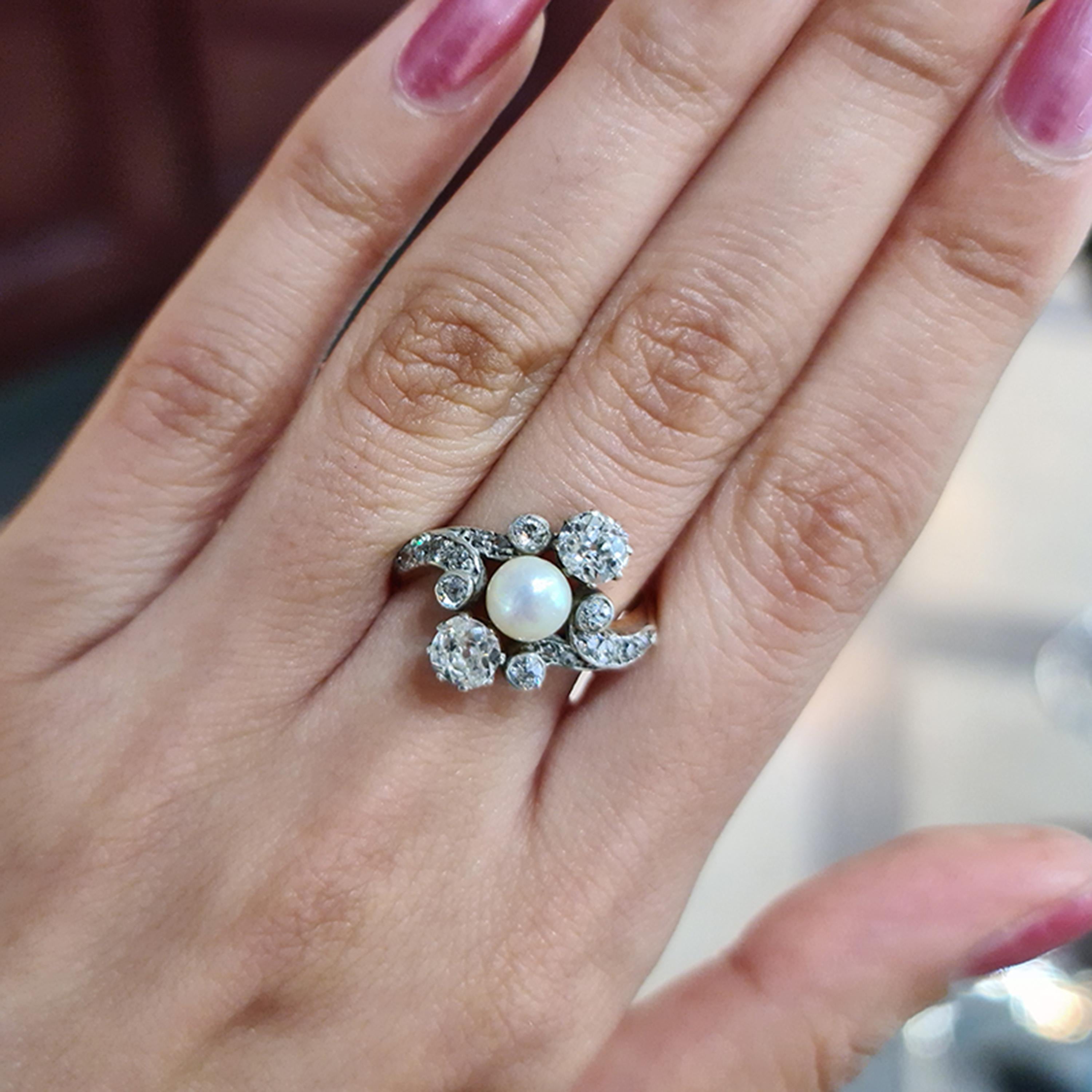 An early twentieth century pearl and diamond, three stone crossover ring, with an Art Nouveau influenced design, set with a natural pearl, between two old-cut diamonds, weighing approximately 1.10 carat in total, in eight claw crown settings, with