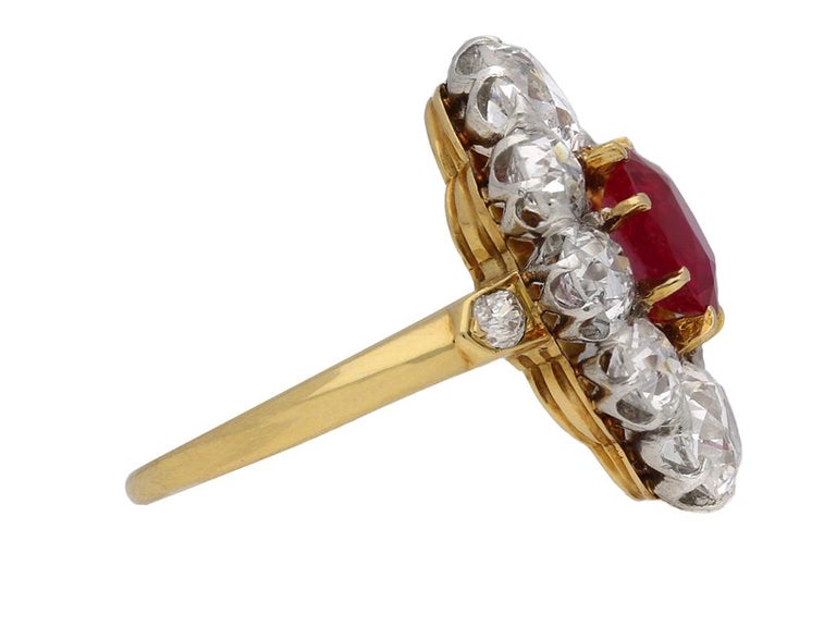 Antique Burmese ruby and diamond cluster ring. Set to centre with an oval old cut natural unenhanced Burmese ruby in an open back claw setting with an approximate weight of 1.70 carats, flanked by two cushion shape old cut diamonds in open back claw