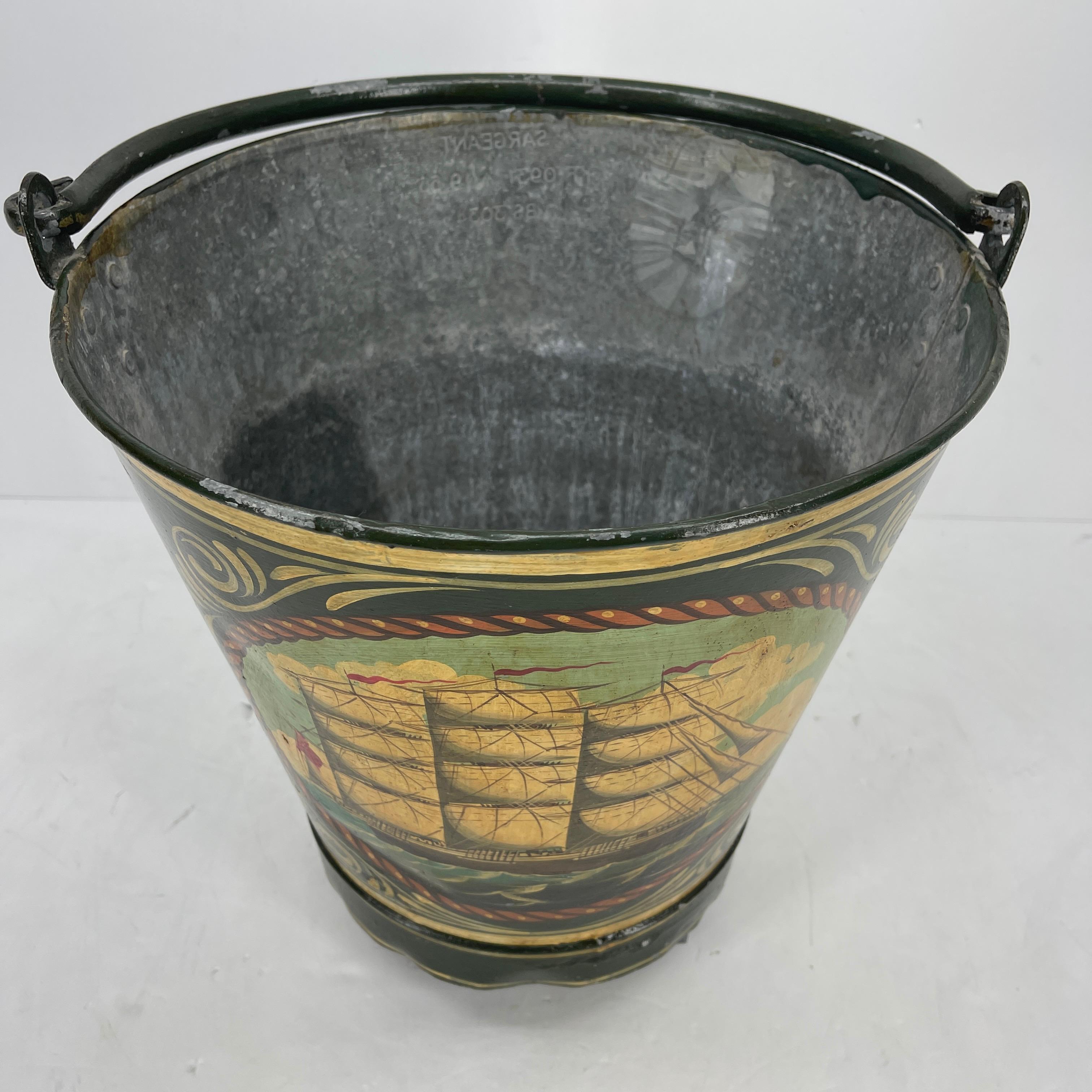 Antique painted metal fireplace log holder bucket. The bucket has a lovely nautical theme; the painted sailboat and rich colors make this functional fireplace accessory a welcome addition to the maritime collectors everywhere.