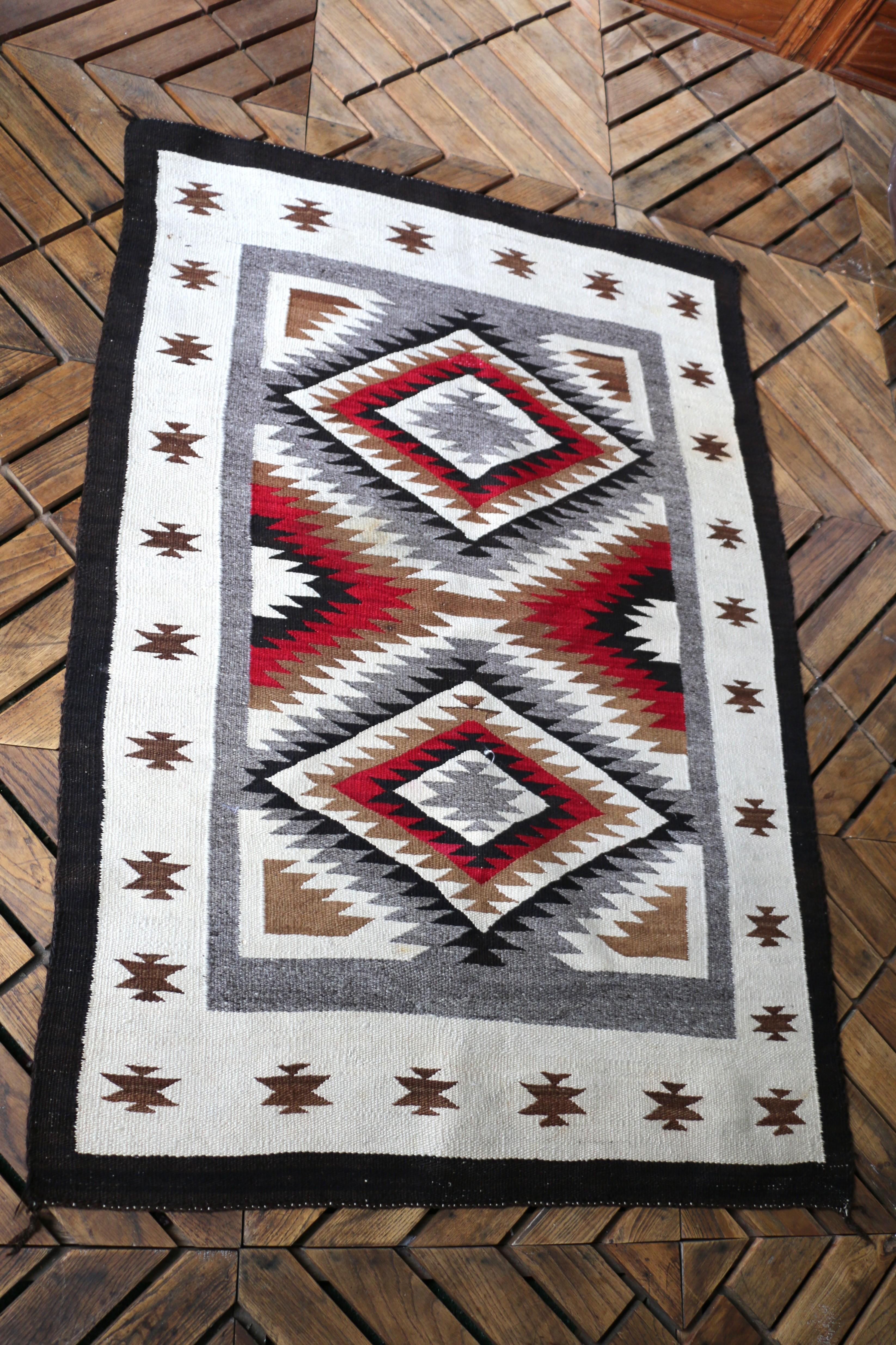 Spectaculaire tapis traditionnel Navajo fabriqué à partir de laine de mouton filée à la main (souvent des moutons Navajo-Churro). Ce tapis se caractérise par ses motifs géométriques distinctifs, connus pour la maîtrise de l'art textile. Les tapis