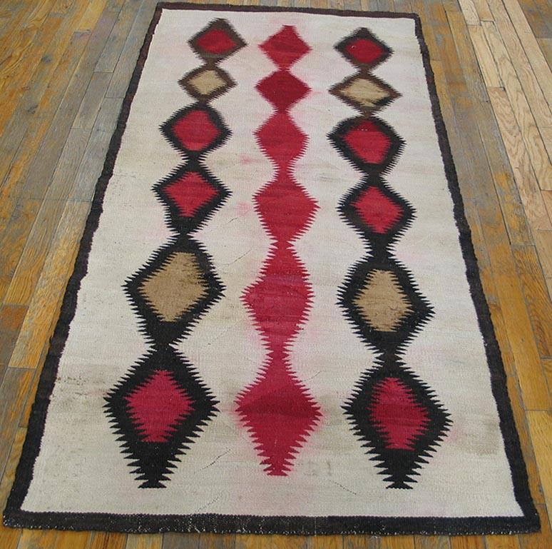 This wonkily woven Native American small long rug shows an ecru field decorated by three independent, floating columns each of six erratically charmingly serrated attached lozenges in charcoal, light camel and richly abrashed soft reds. Central