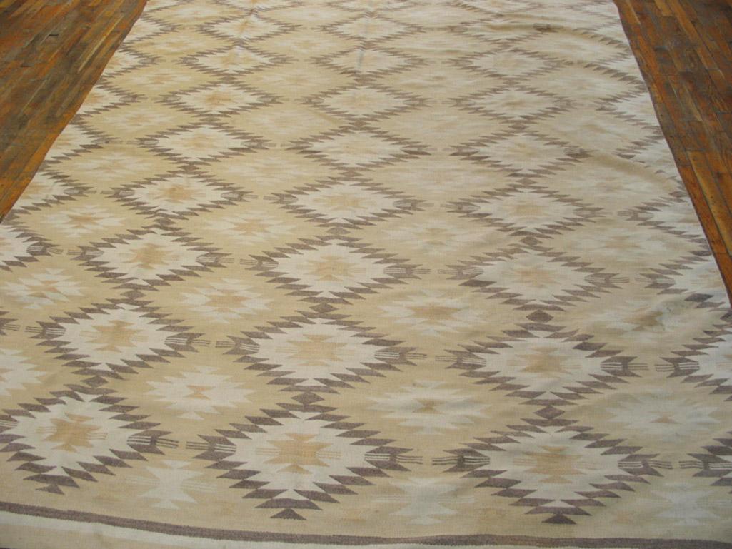 This rare format antique Navajo carpet displays a rather soft palette of cream, straw, rust-tan, and sandy camel in three columns of nine serrated, connected lozenges and similar half-columns on the sides. Narrow end stripe borders. Excellent