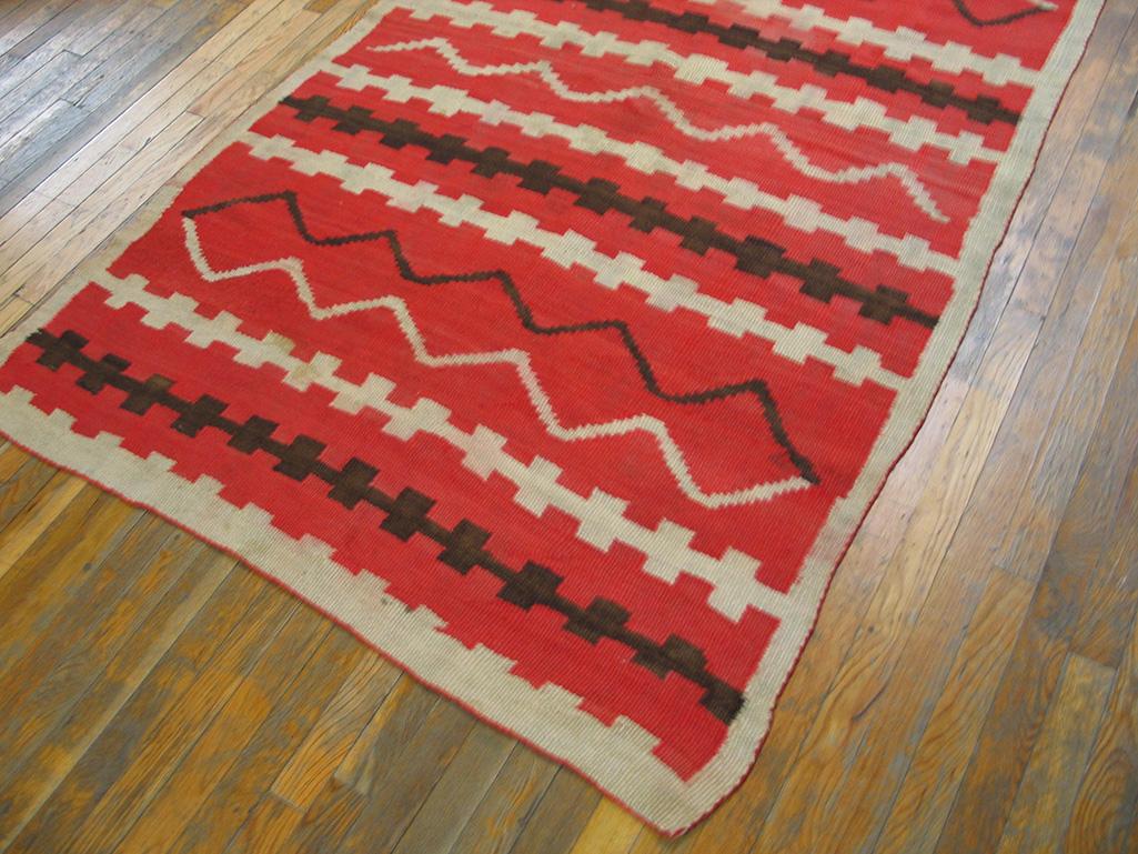 Orangy-red dominates this 19th century Southwestern rustic scatter in the style of the Classic Style blankets of the 1870s. Zig-zags, single or doubled, alternate in panels with blocks on bars, all within a narrow plain off white wool border. 
The