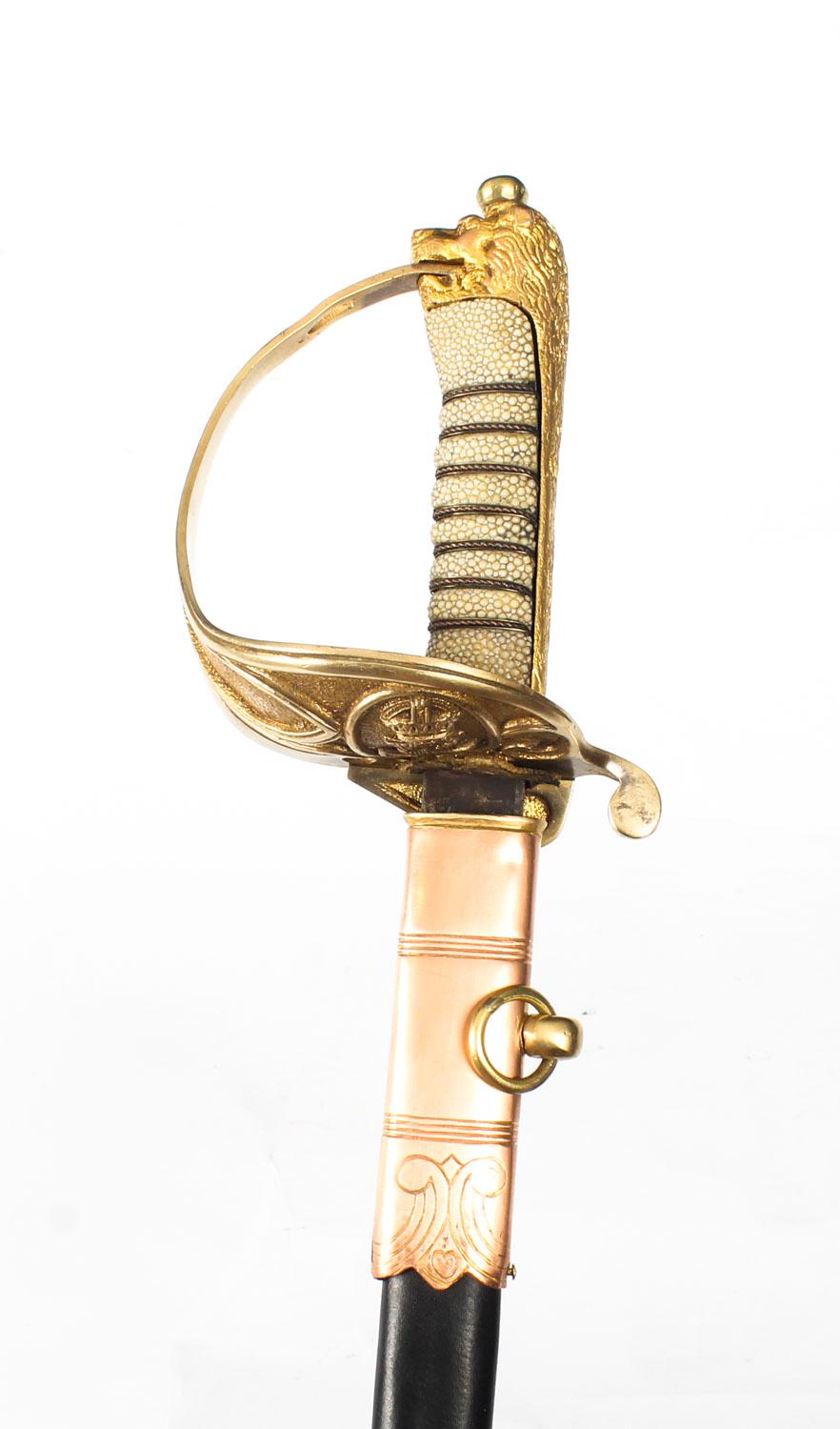 A superb antique Naval Officers Sword in leather mounted scabbard by H.A. Friedberg, 8 Queens Street, London, stamped 1897.

The sword features a brass foliage basket with a crown and anchor plaque and a decorative shagreen hilt that terminates in