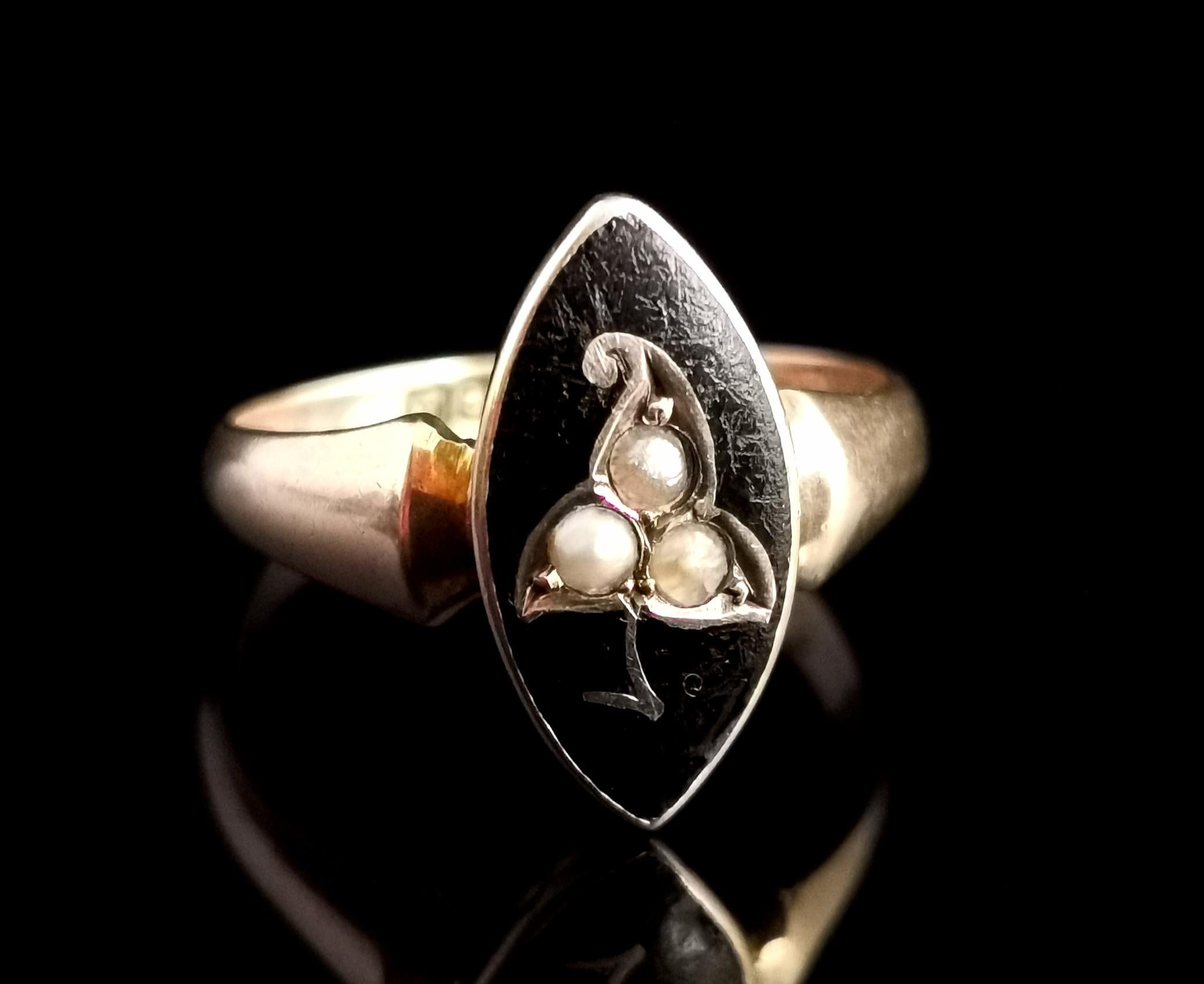 A beautiful antique early Art Deco era mourning ring

It is a navette shaped ring with an elongated central black enamelled panel set with three split pearls, the pearls arranged to form an ivy leaf.

It has chunky raised shoulders and a smooth