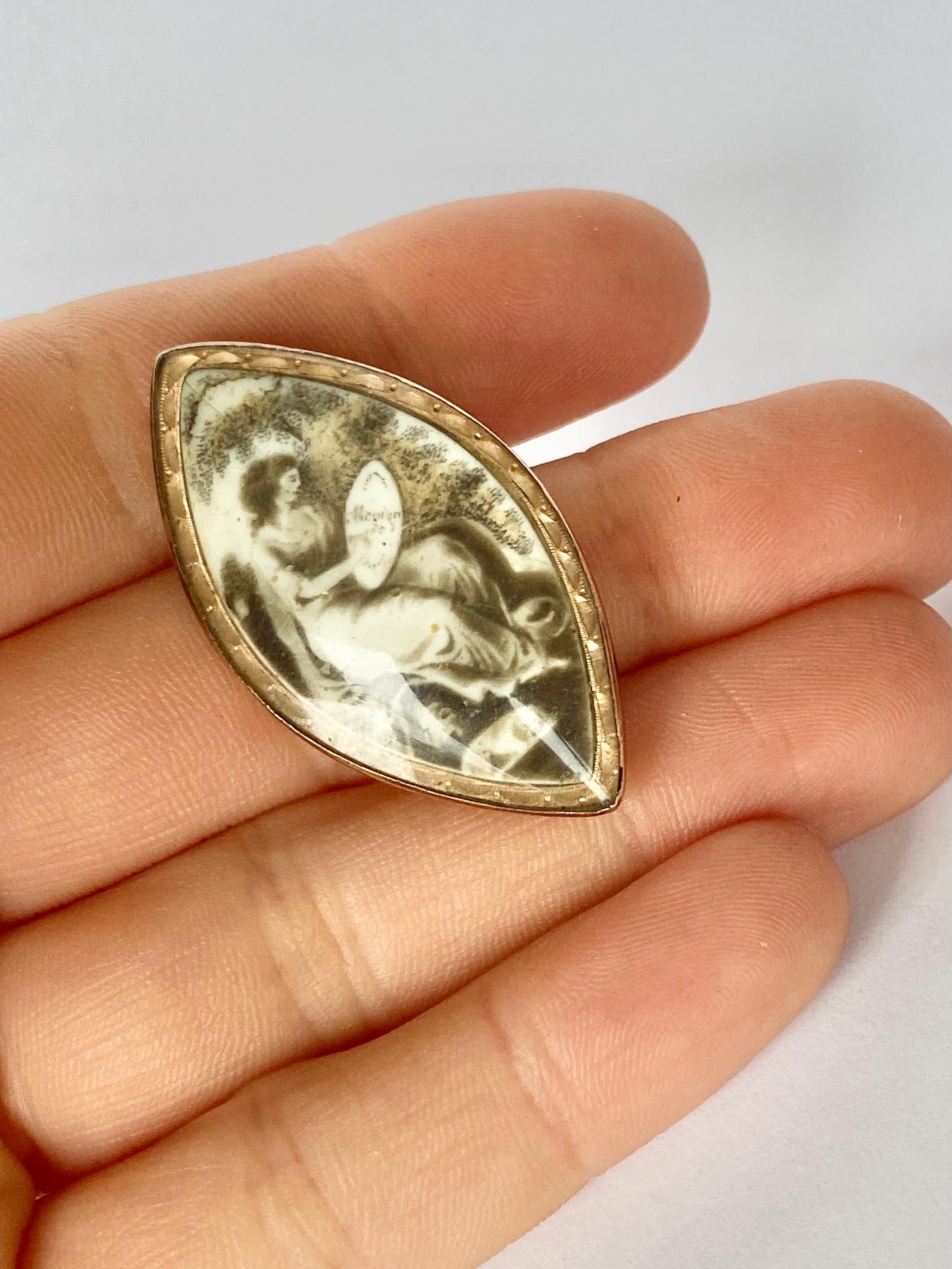 A spectacular antique Georgian brooch set with a stunning navette shaped sepia. The sepia features a scene with a woman in mourning. Modelled in 9 carat yellow gold.

Sepia dimensions: 38x21mm

Weight: 5.6g