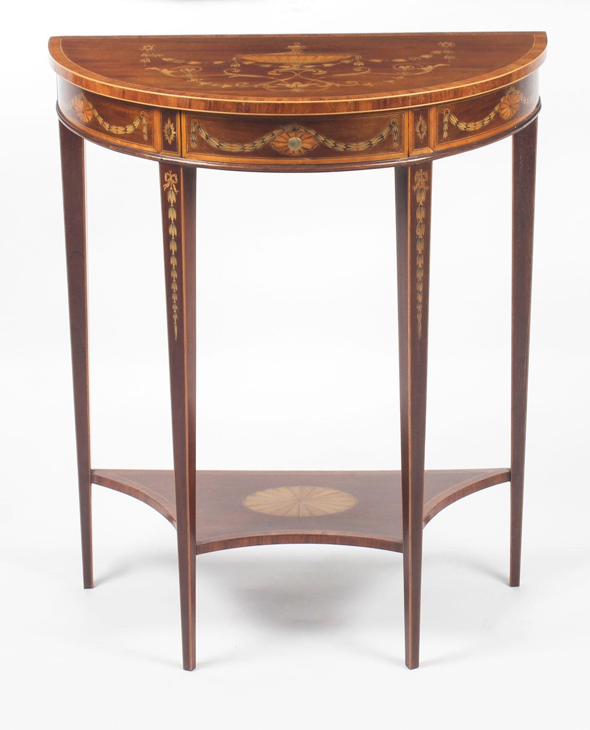 This is a beautiful antique near pair of English Regency Revival mahogany and marquetry demilune console tables, late 19th century in date.

The half-round table tops are beautifully framed with a satinwood border and have a finely inlaid