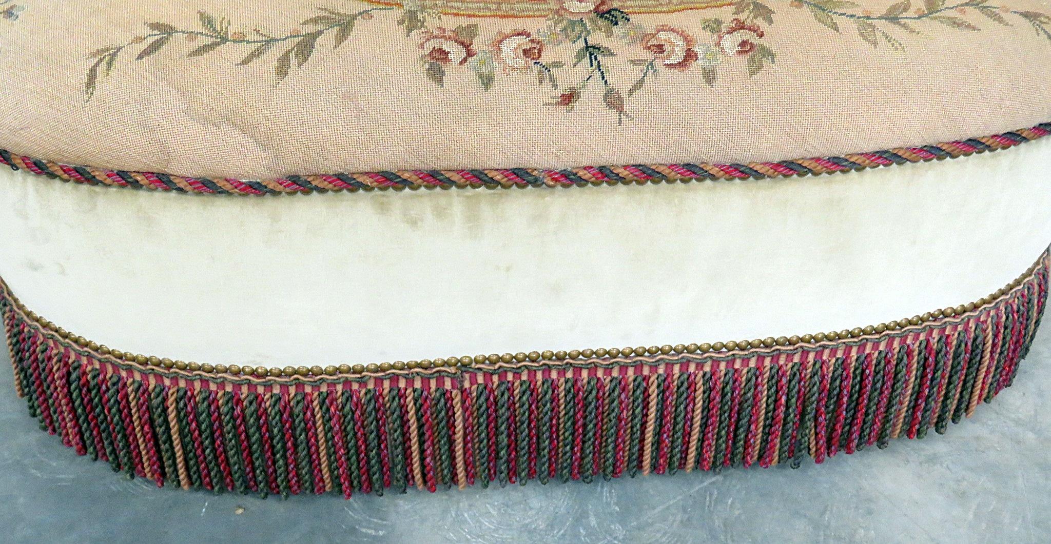 Antique needlepoint footstool with tassel trim.