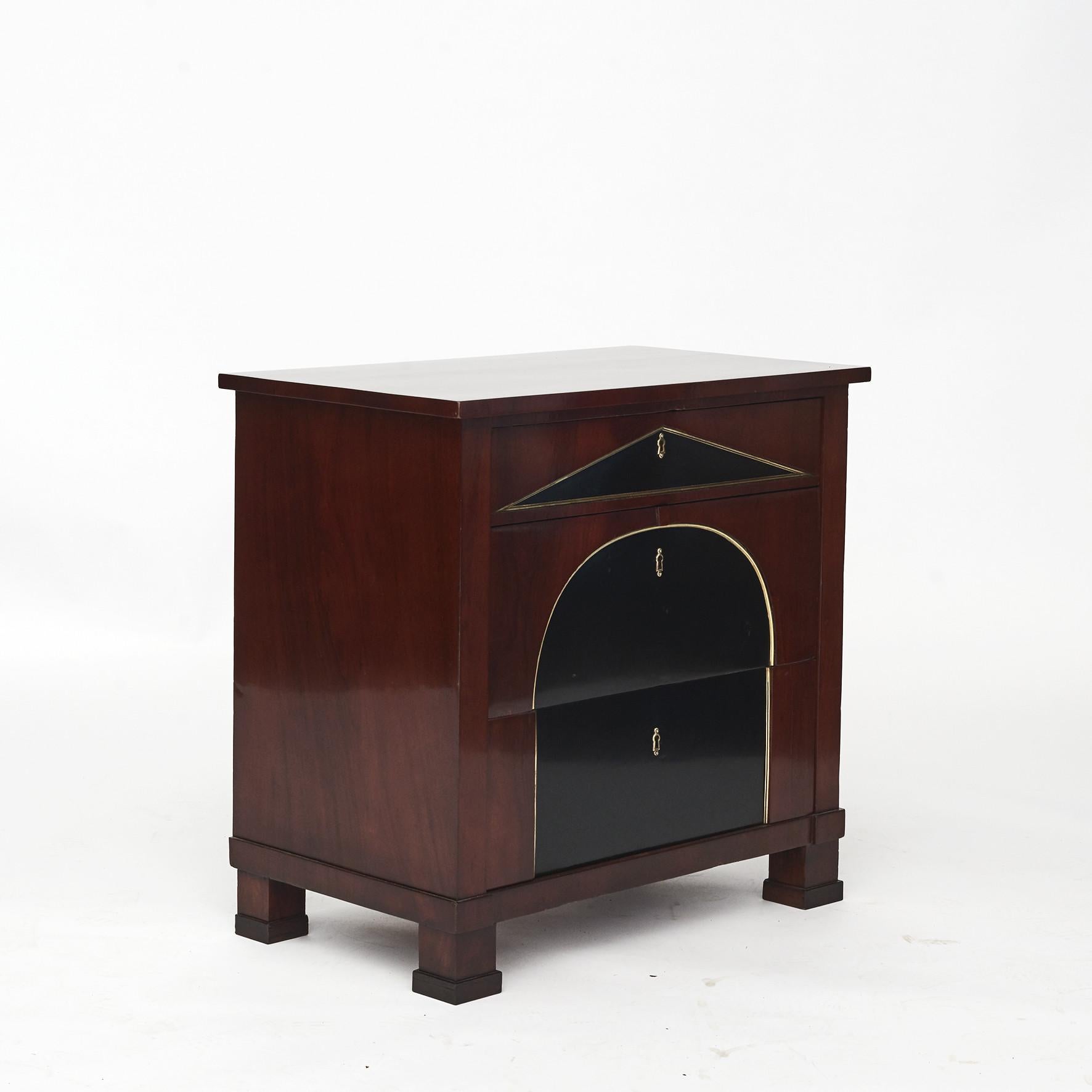 Neo classicist mahogany chest of drawers with 3 drawers.
The top drawer with triangle, ebonized mahogany surrounded by profiled gilt bronze molding.
Two lower drawers with an arched ebonized mahogany surrounded by profiled gilt bronze